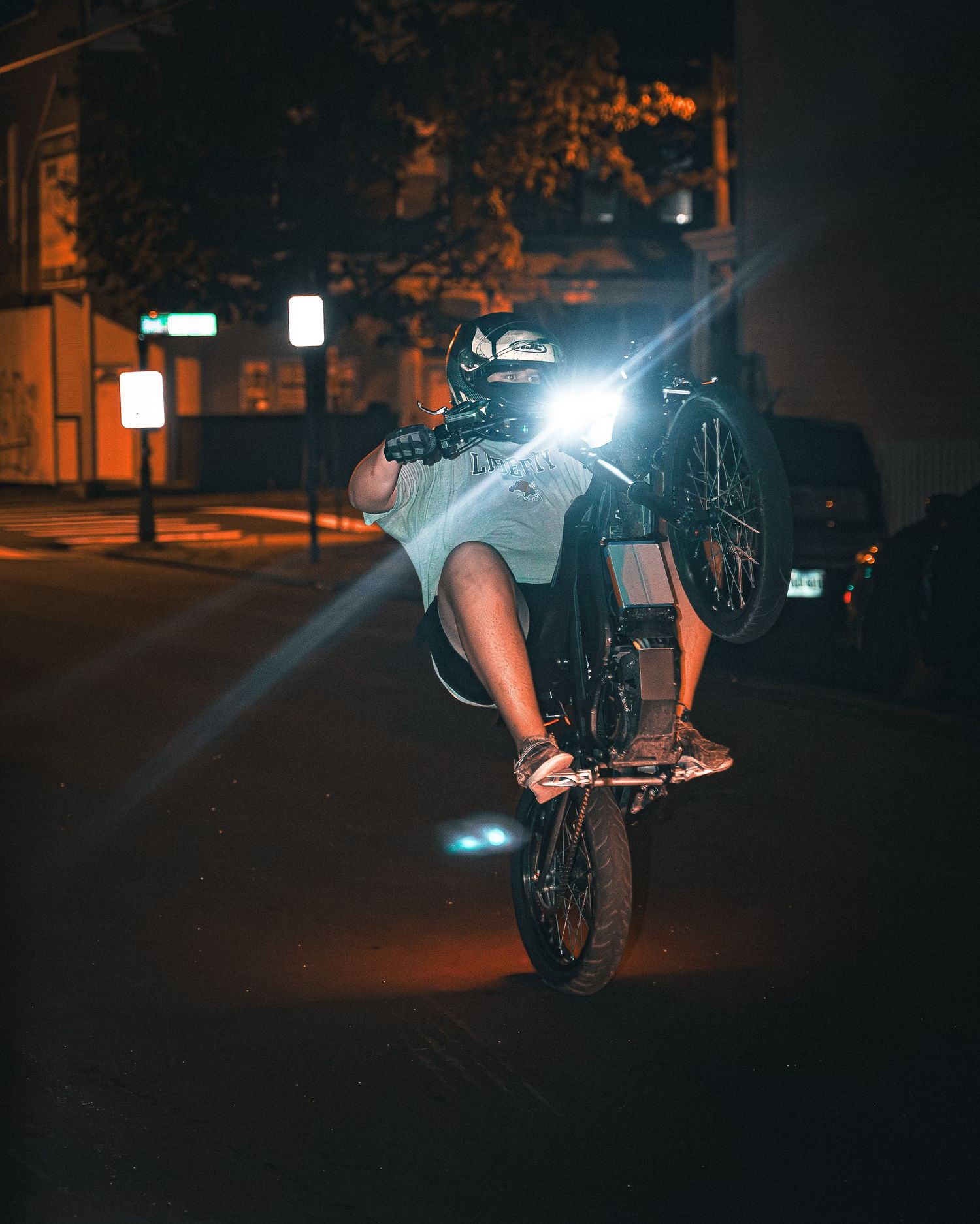 Night BMX rider performing stunts illuminated by street lights in an urban setting.