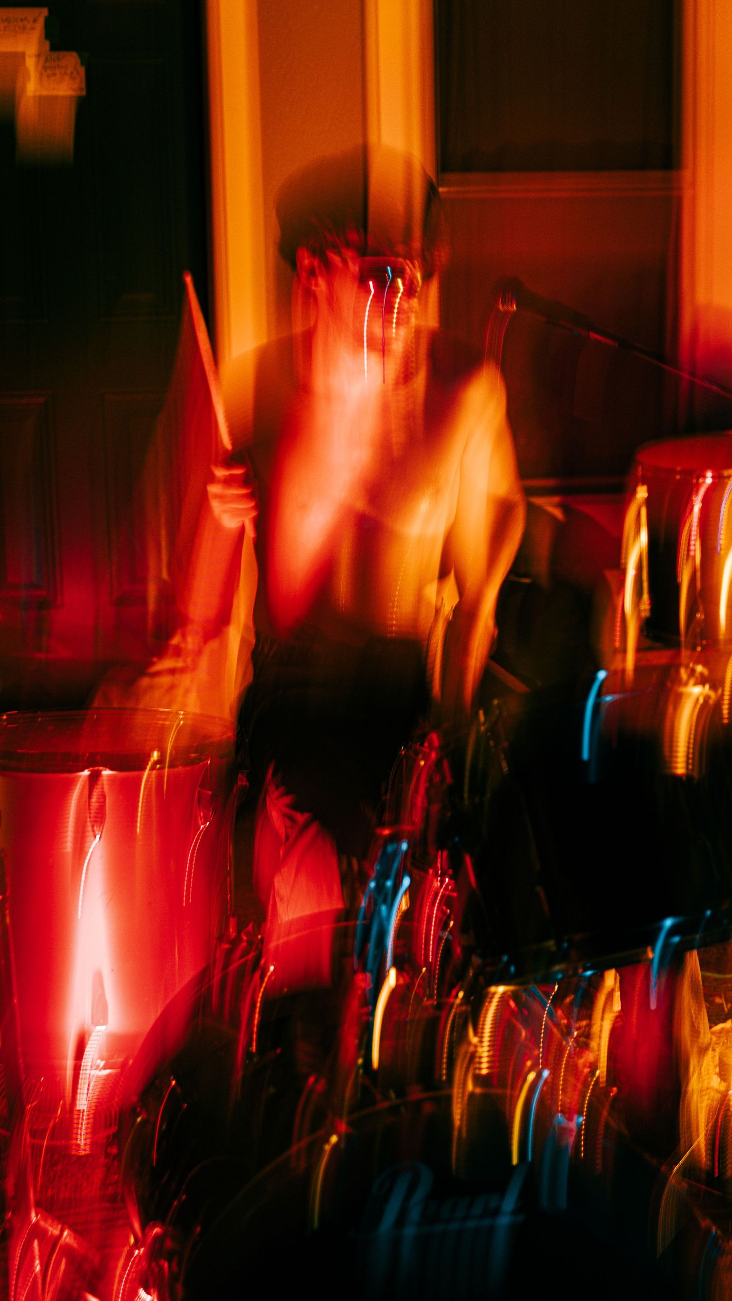 Long exposure photograph creating abstract streaks of red, orange and blue light in a dark performance space.