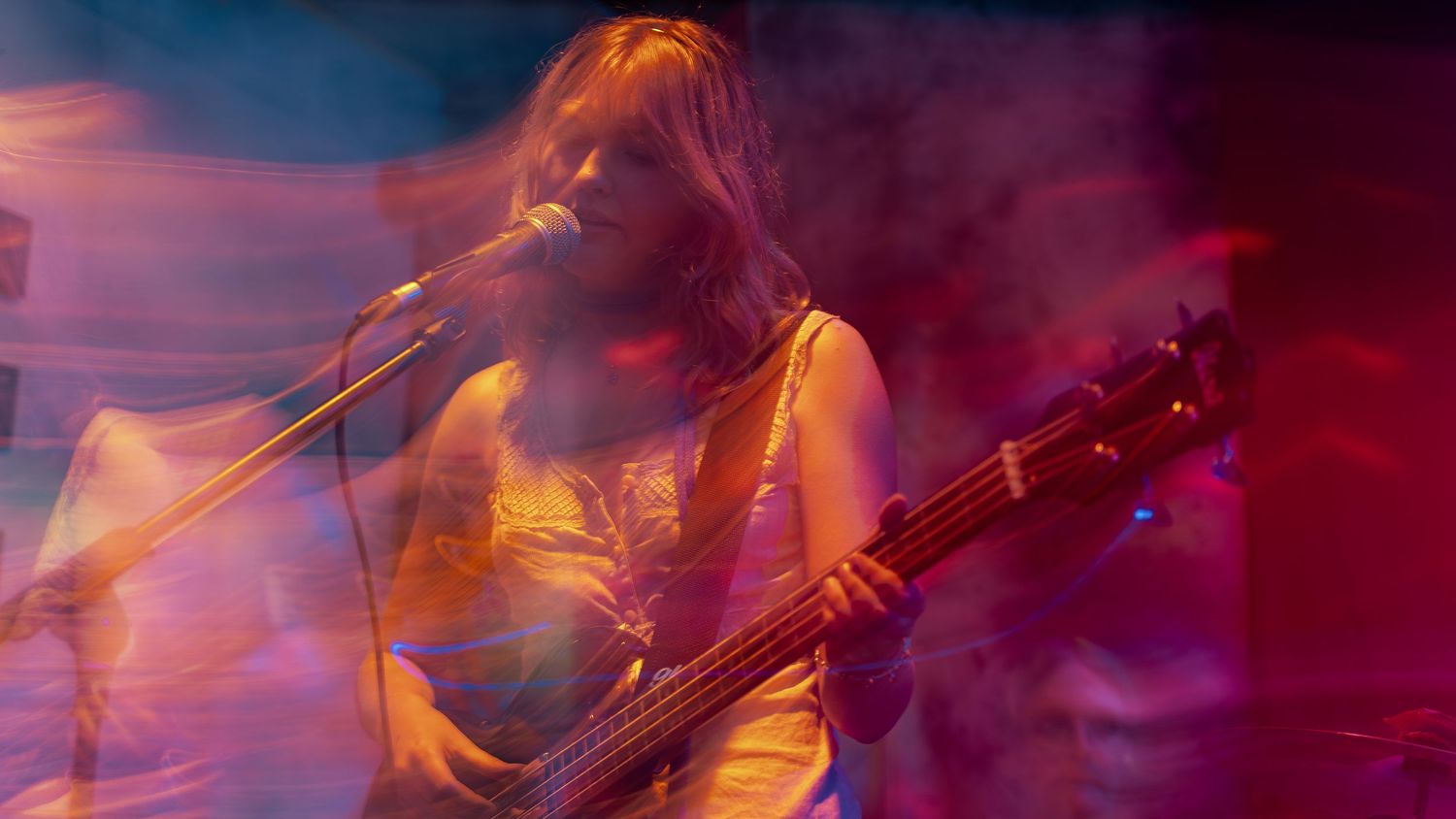 Abstract music performance photo with red and purple lighting effects creating a dreamy atmosphere.