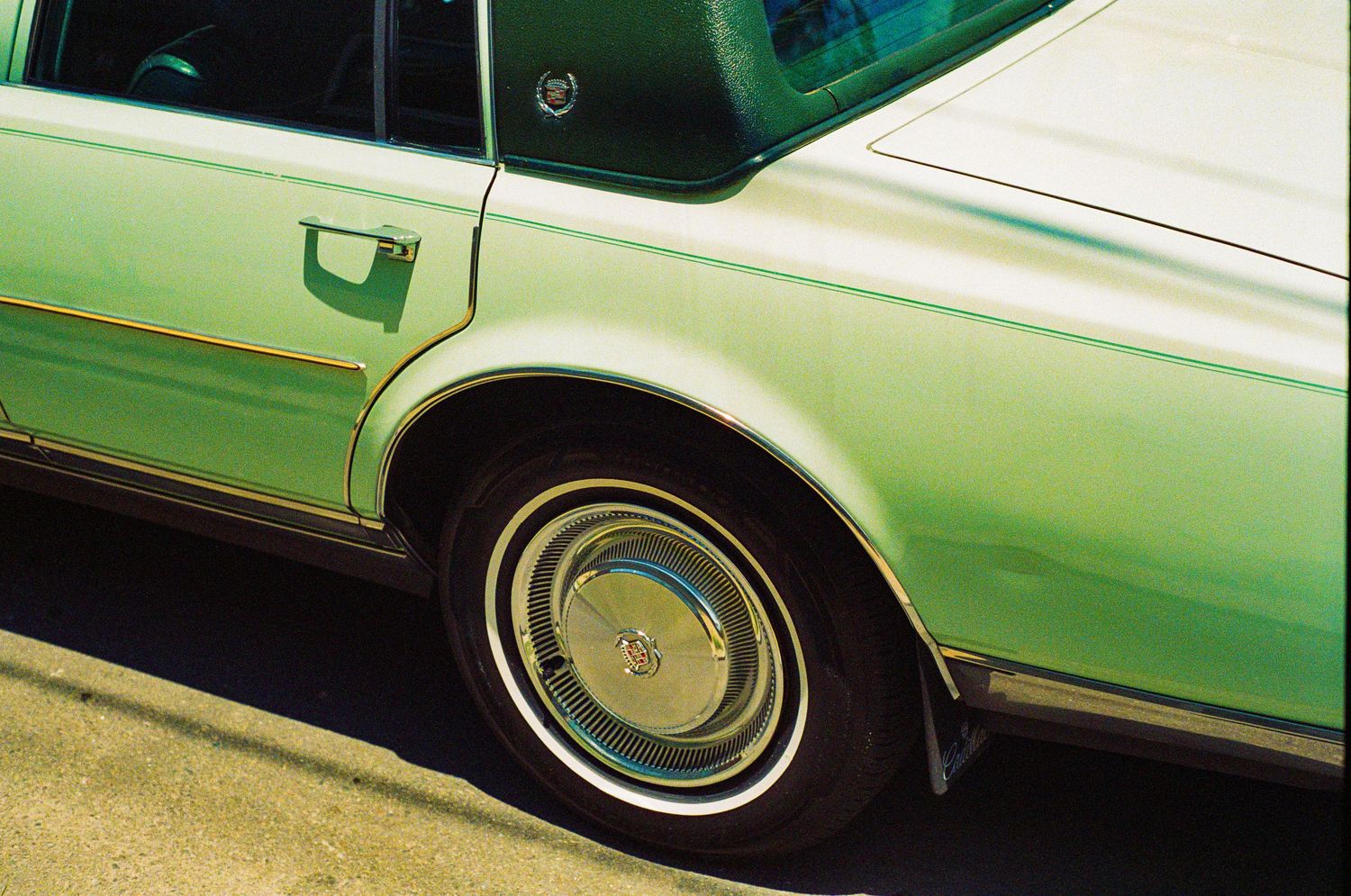 Close-up of a mint green classic car's wheel well and chrome hubcap detail.