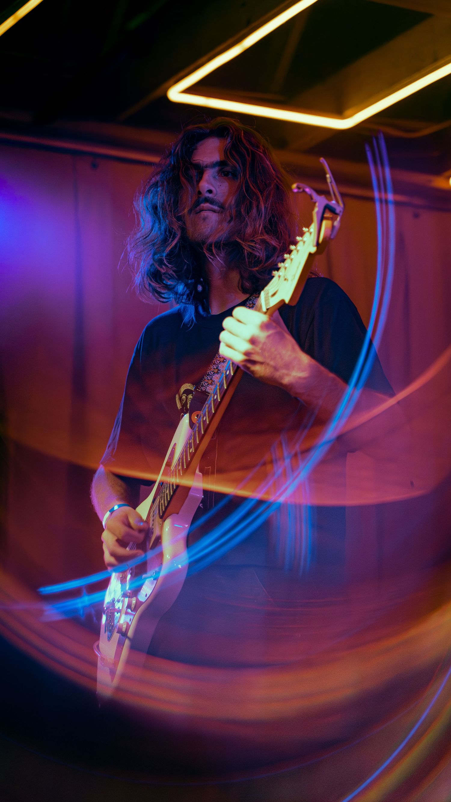 Motion-blurred photos of guitarist performing under dramatic red and blue stage lighting create dynamic visual effect.