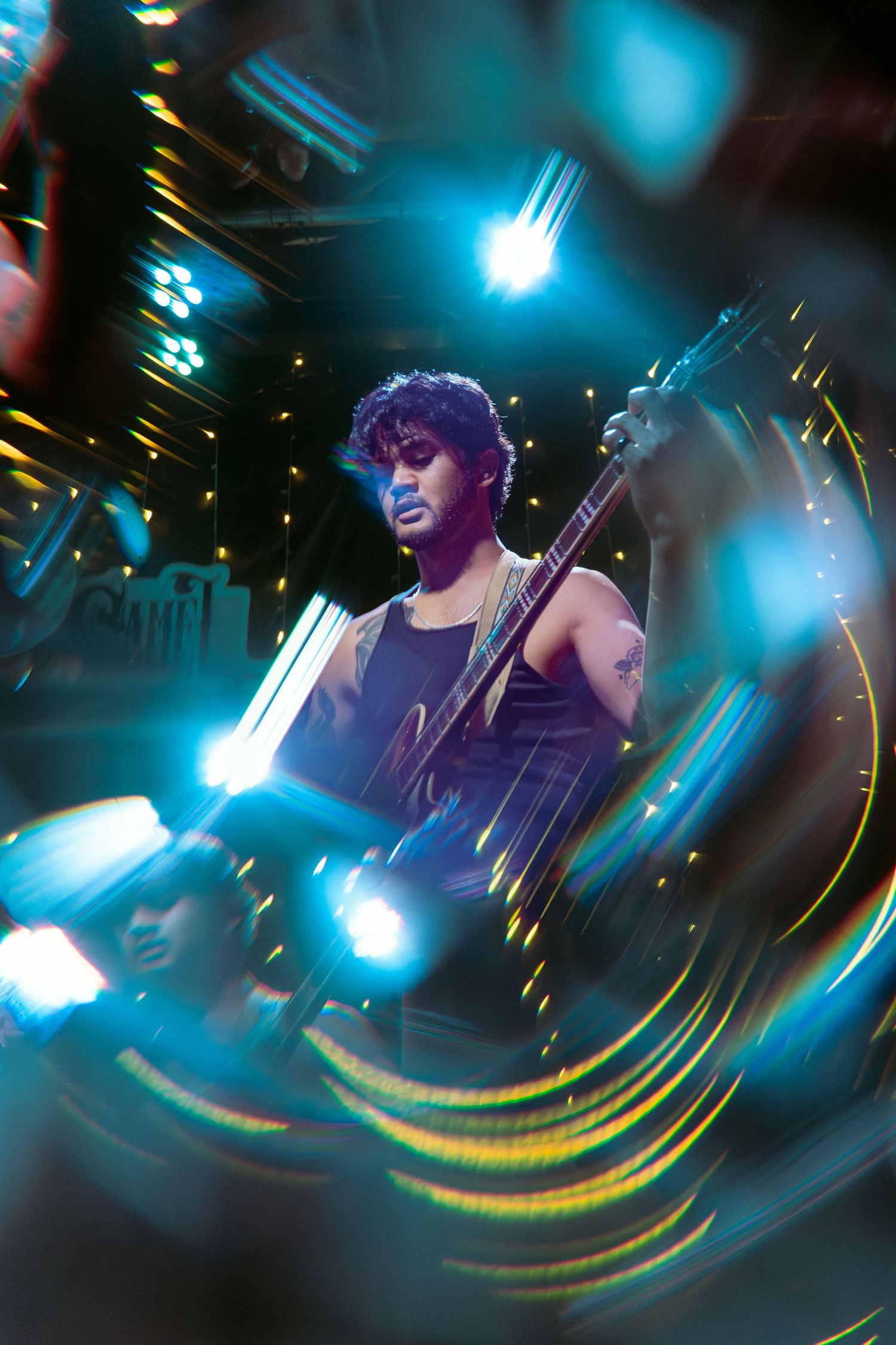 Concert musician performs on guitar under dramatic blue stage lighting with motion blur effects creating a dynamic atmosphere.