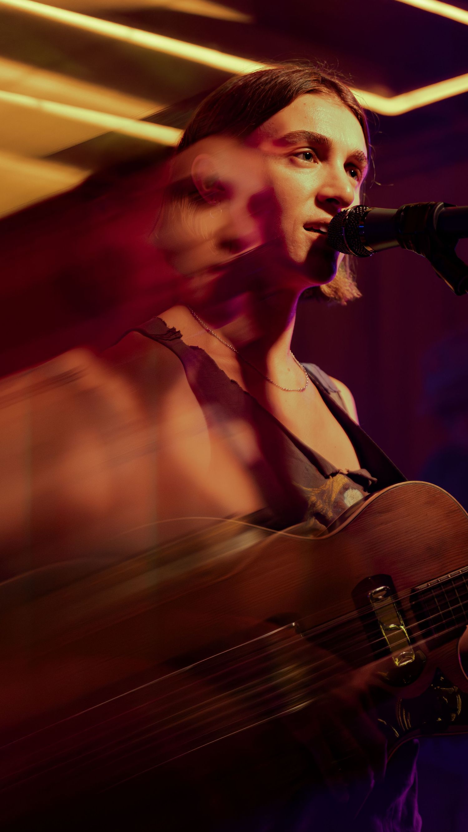 A musician performs on stage with dramatic lighting creating motion blur effects during a live concert performance.