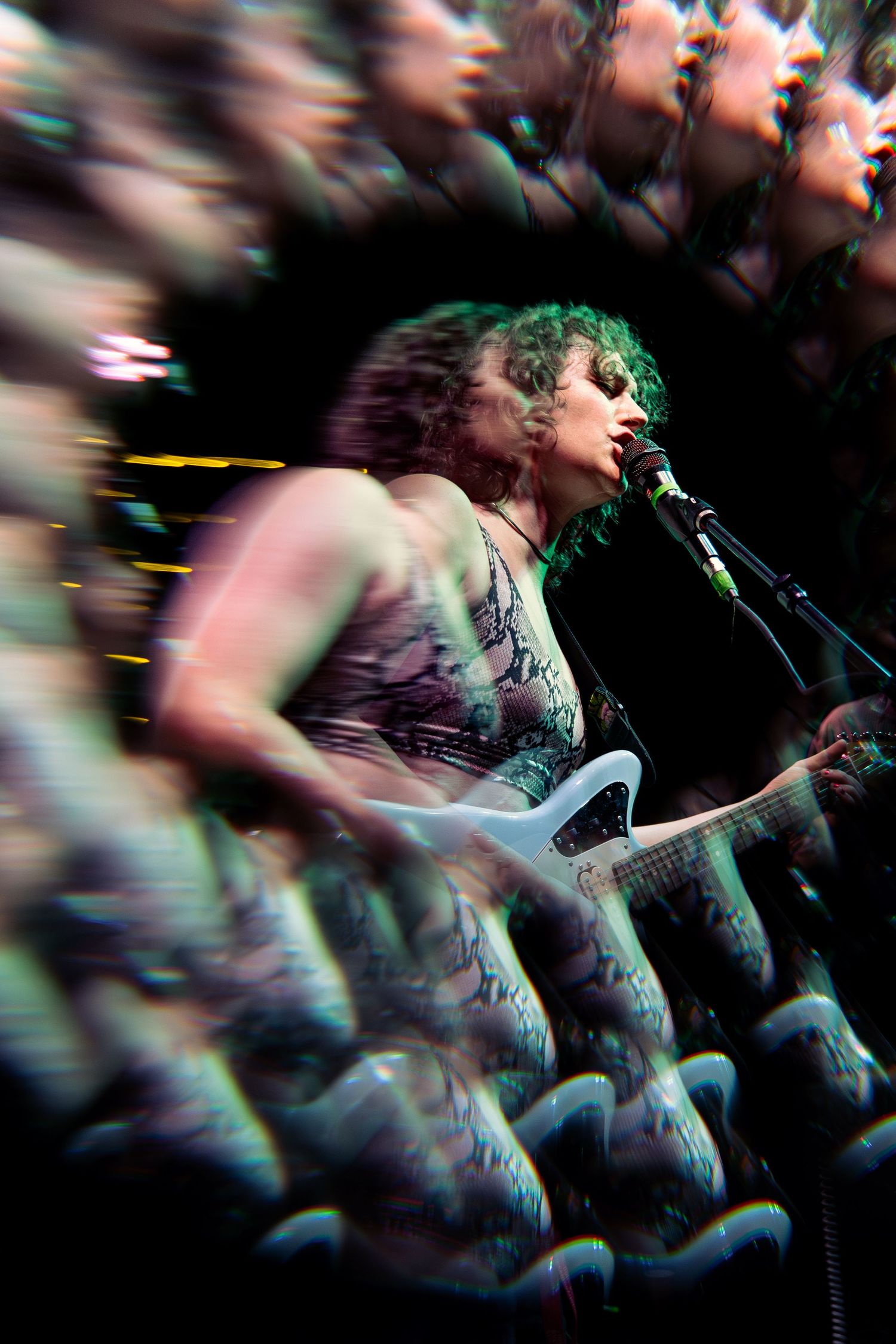 Motion blur creates an artistic effect of people dancing at a concert with tinted lighting and silhouettes.