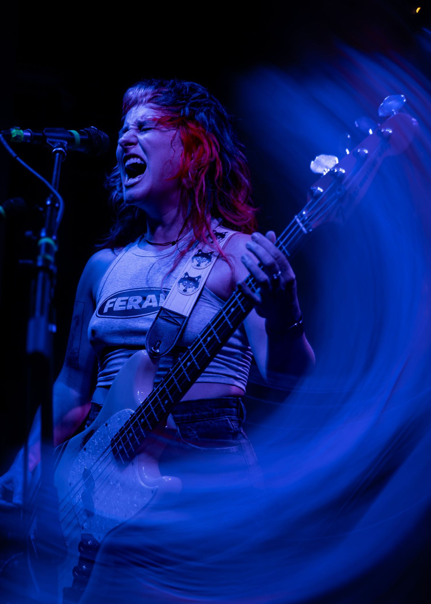 Multiple action shots of a performer with guitar riffing energetically on stage under dramatic blue lighting during a show.