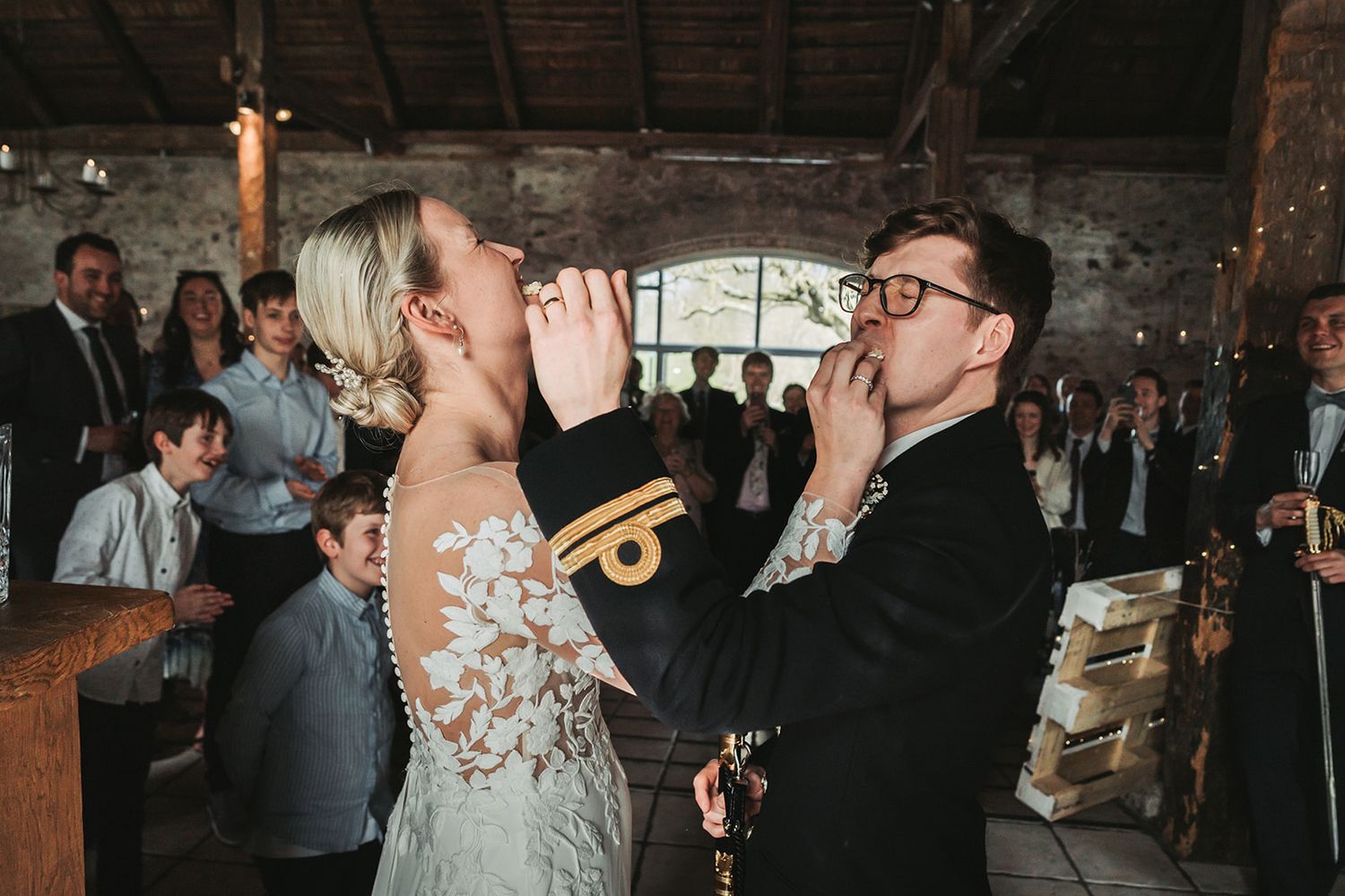 Candid moments captured at a rustic indoor wedding reception with guests mingling and dancing.