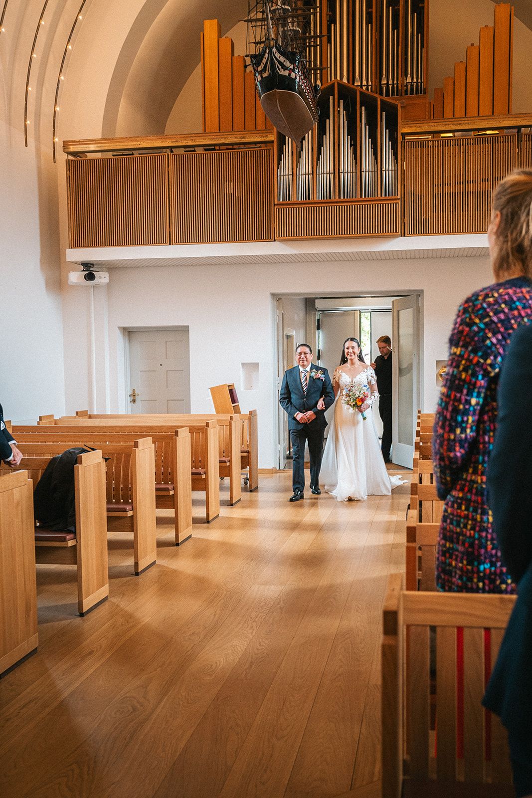 Church wedding processional sequence showing a bride walking down a wood-floored aisle with pews and an organ.