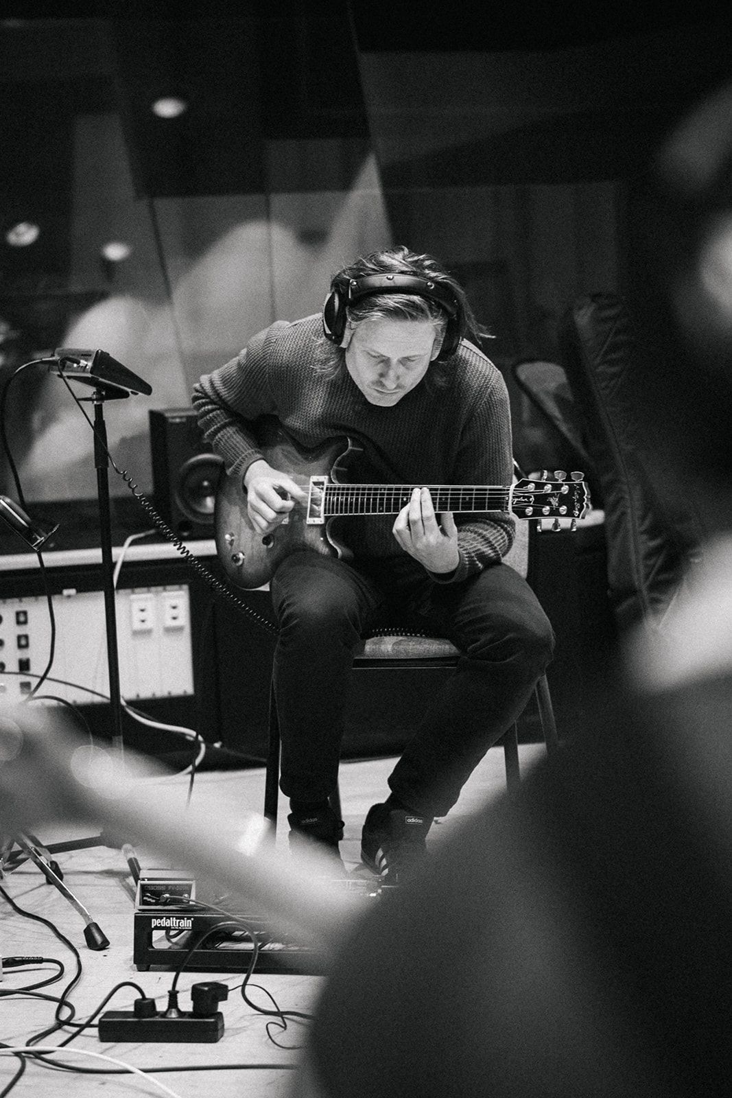 Black and white artistic photos show a guitarist performing and recording with equipment in a dark studio setting.