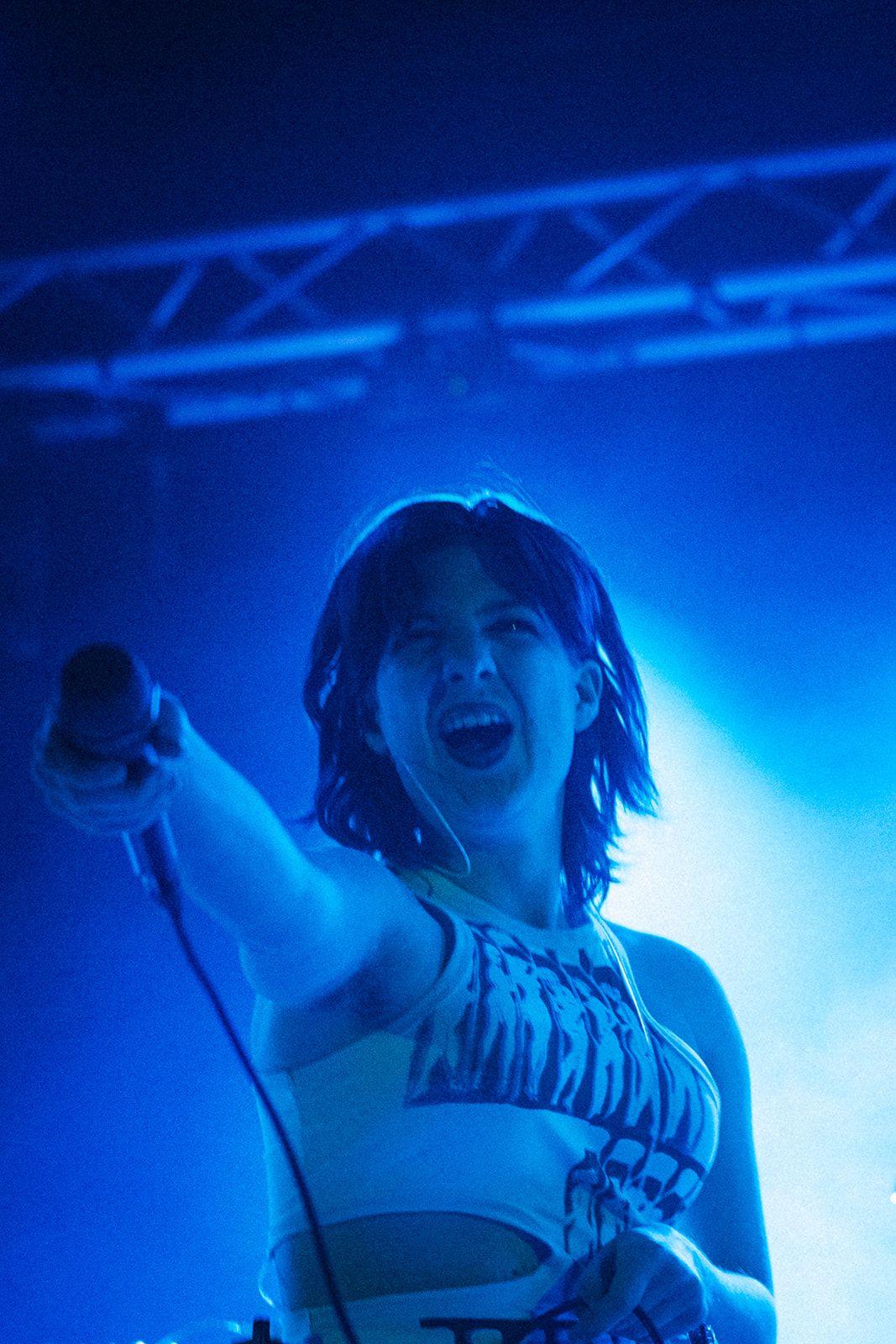 A performer dances under dramatic blue stage lighting at a concert venue.