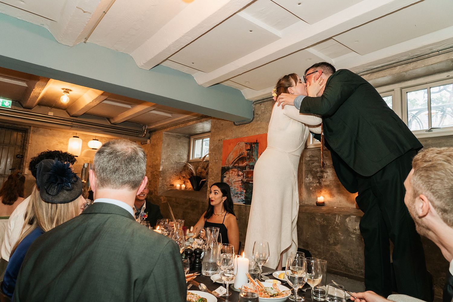 Wedding celebration at indoor reception with couple performing romantic dip dance move while guests look on from tables.