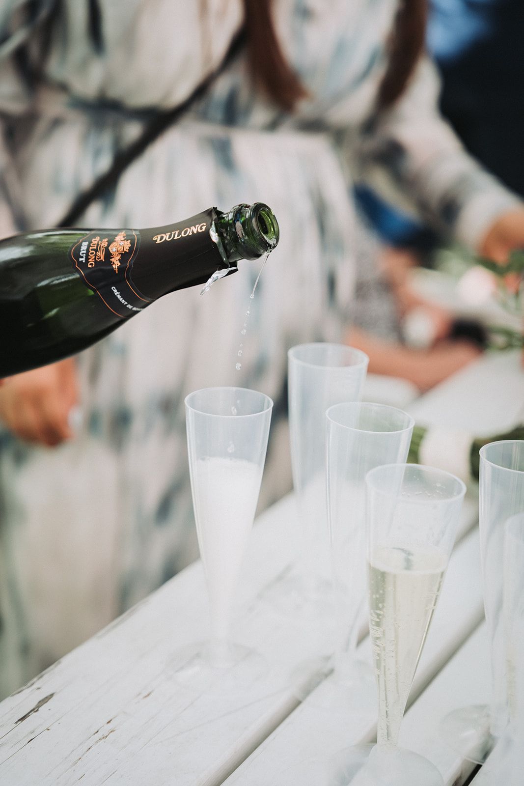 Champagne being poured into elegant flute glasses on a white wooden surface during a celebration event.