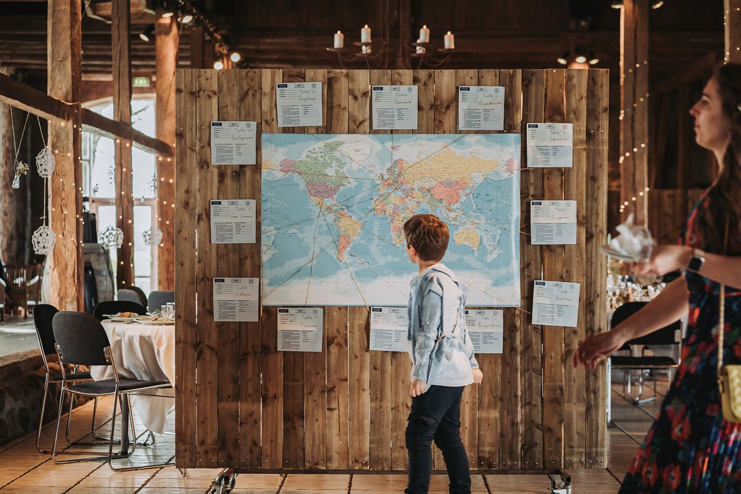 A rustic indoor venue decorated with string lights and wooden walls displaying vintage maps and artwork.