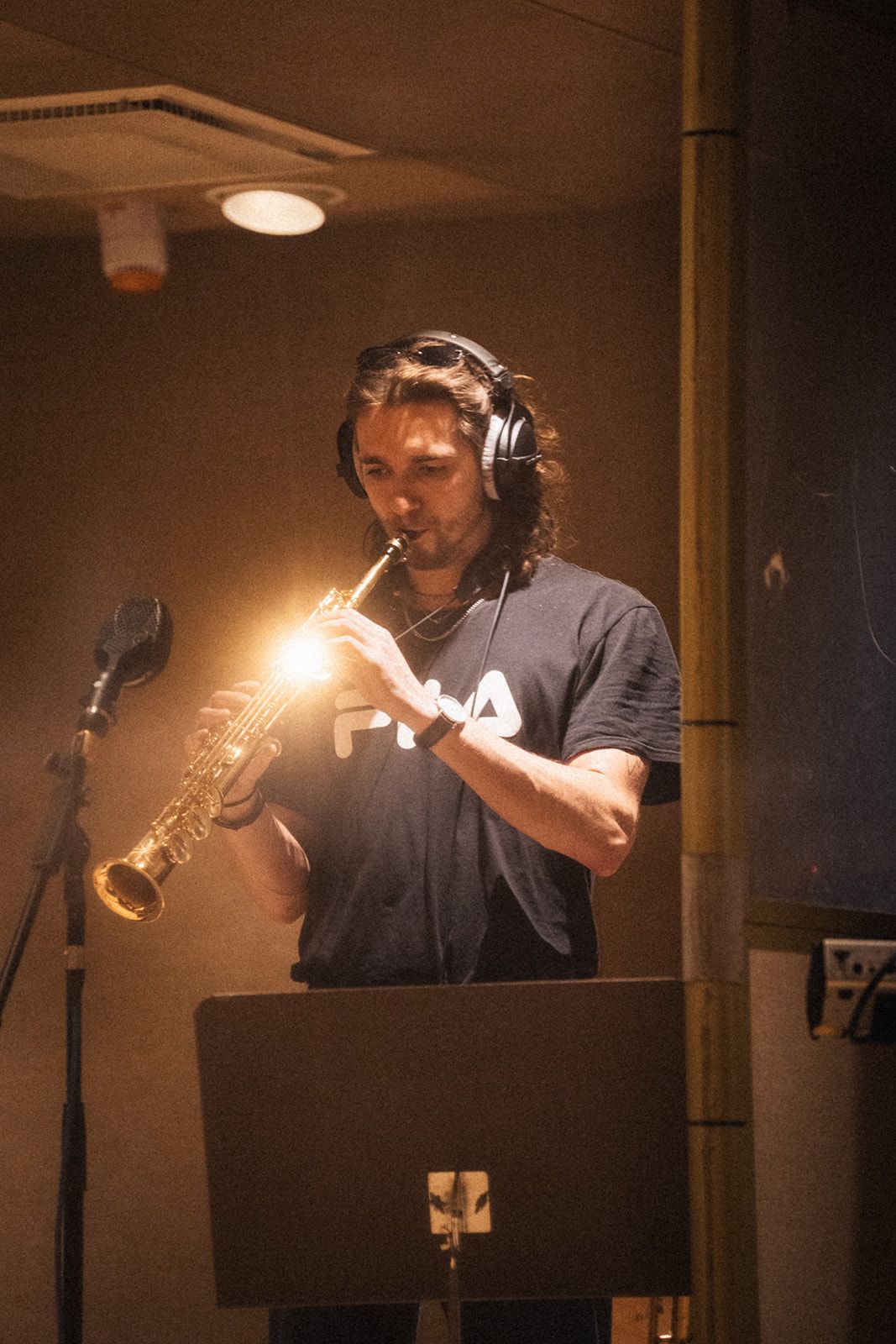 Musicians performing in a dimly lit recording studio with brass instruments and headphones.
