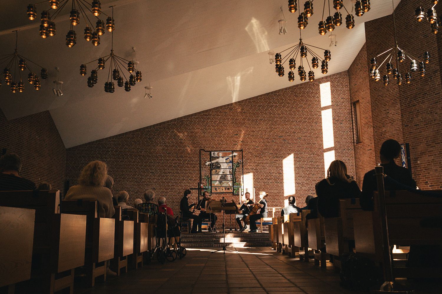 Multiple pendant lights hang from a dark ceiling above a long table in a dimly lit interior space.