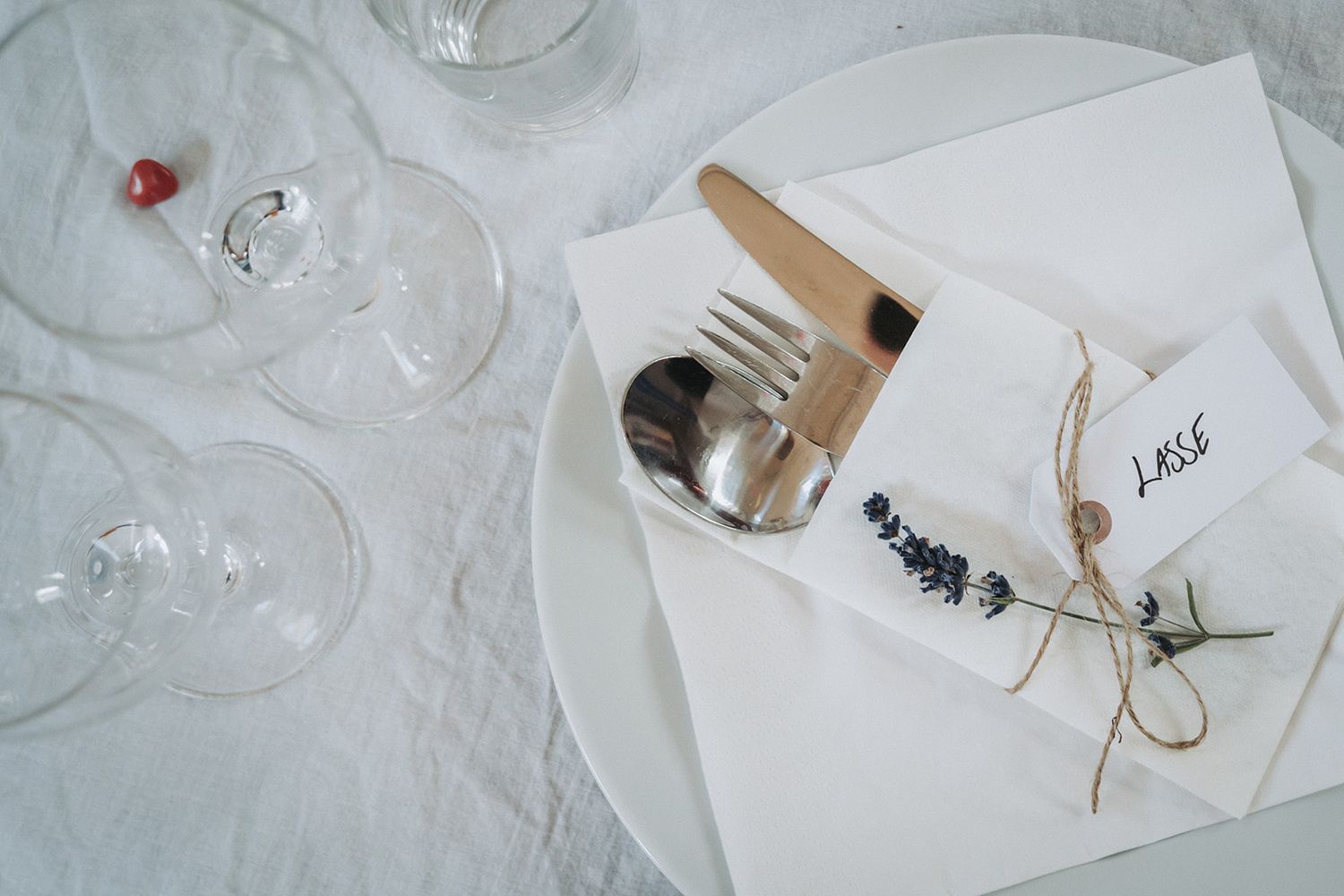 Overhead view of a spilled wine glass on a white tablecloth with an elegant table setting and scattered items.