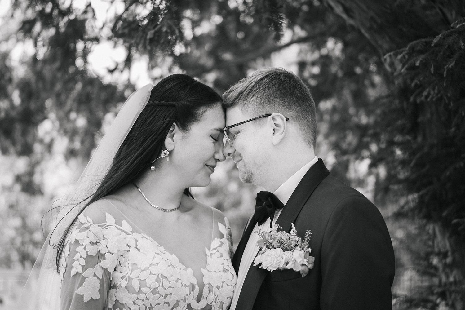 Black and white romantic wedding portraits of a couple embracing under trees in an outdoor garden setting.