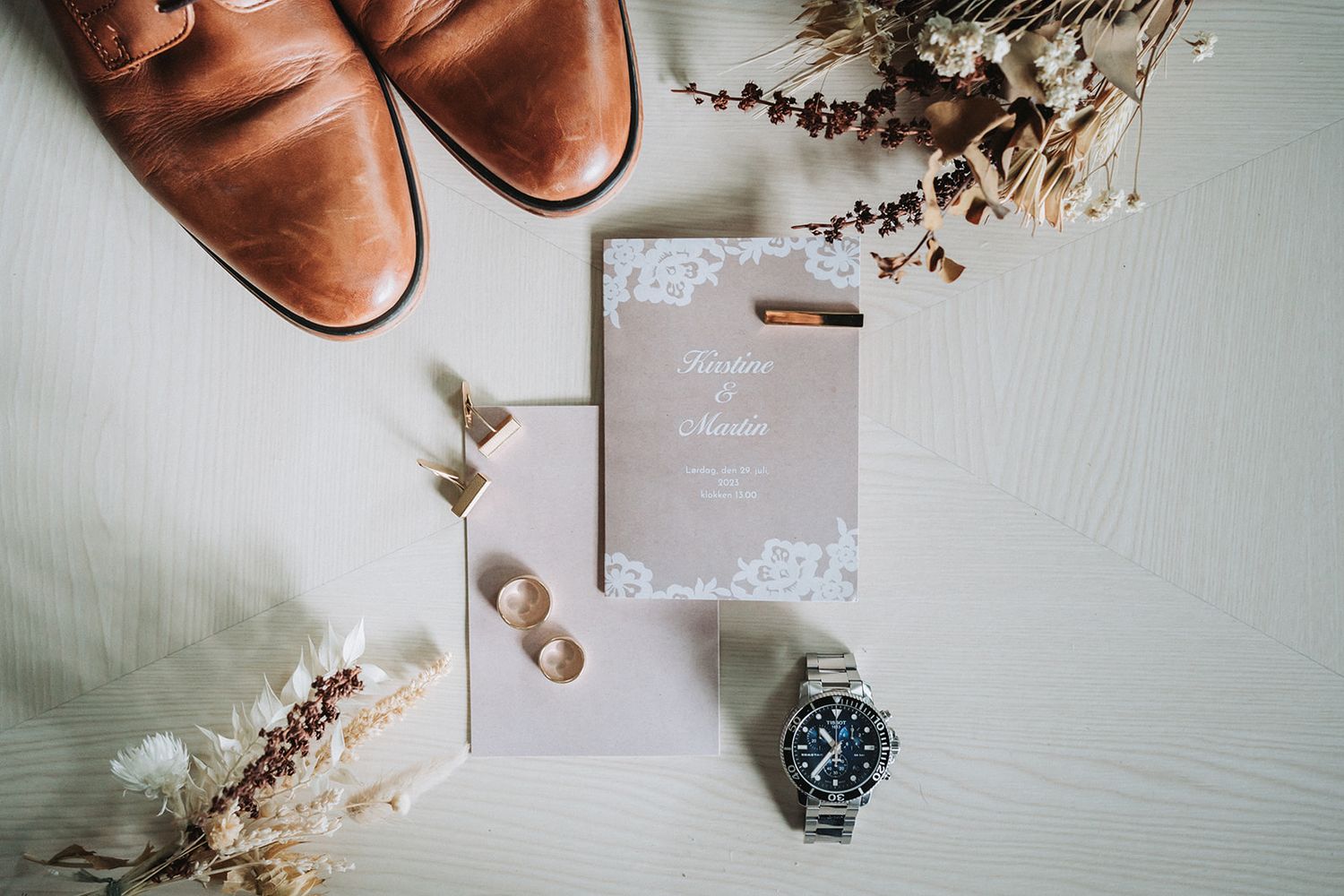 A compilation of romantic wedding details featuring rings, dried flowers and elegant decor on a light colored background.