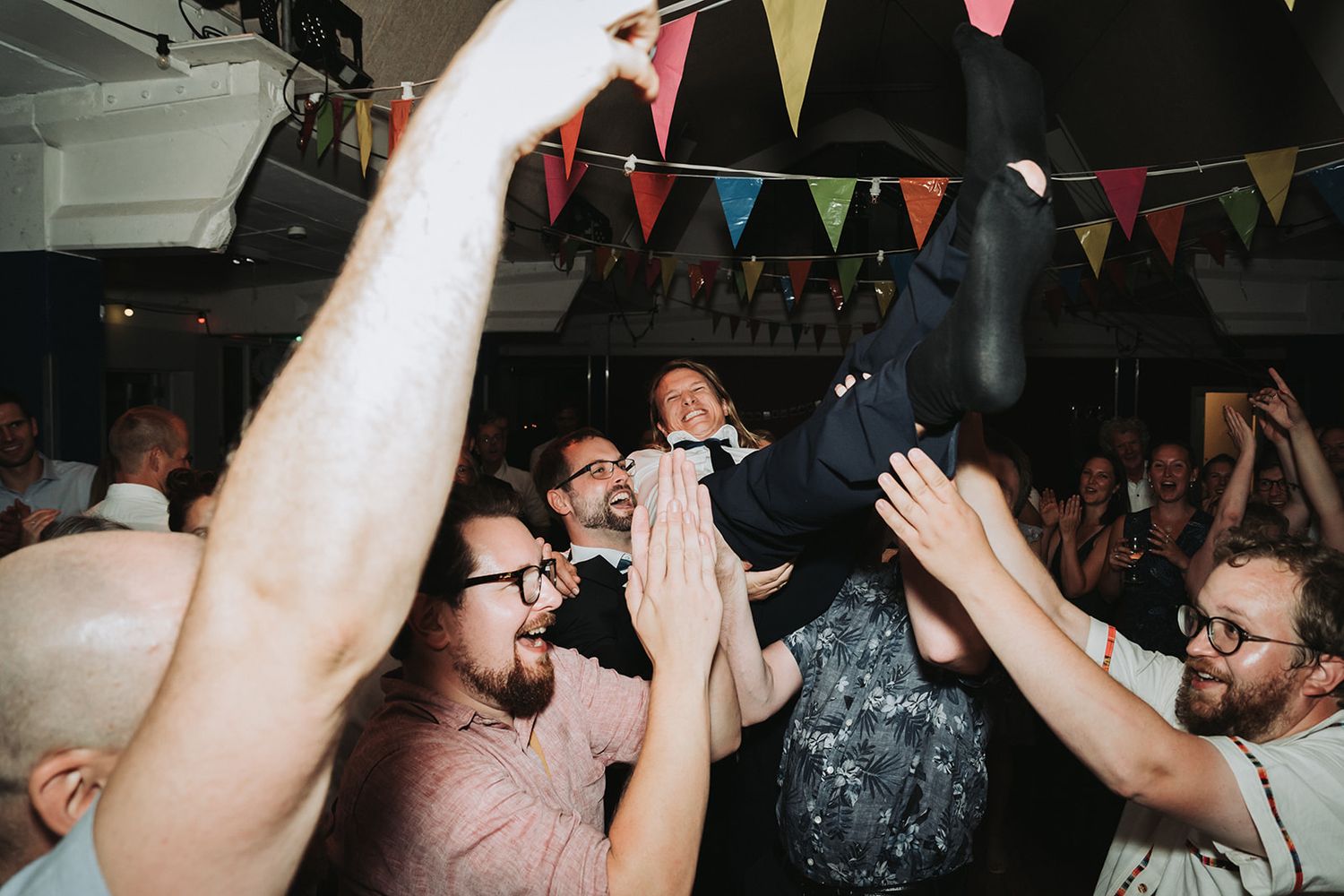 Energetic crowds cheering with raised arms at a lively indoor celebration event.