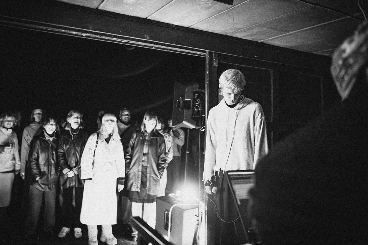 A group of people standing together in a dimly lit space captured in black and white photography.