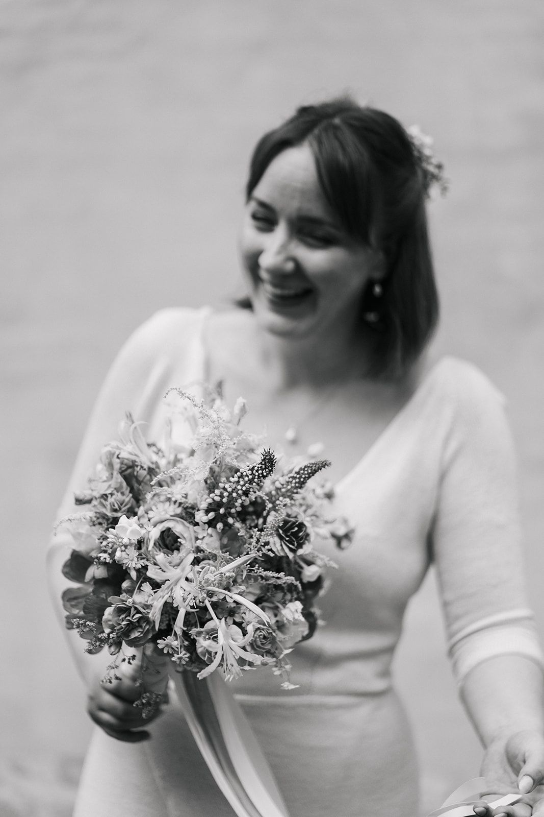 Black and white series of photos showing a bride displaying a wedding bouquet of mixed flowers and greenery.