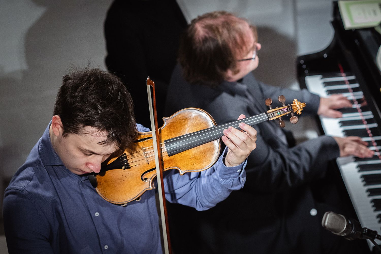Musicians perform together with violin and piano during a classical music concert.