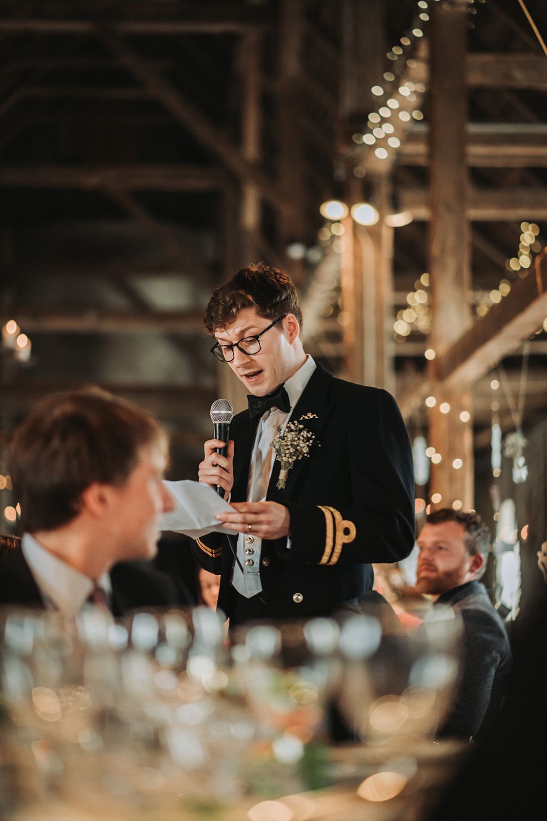 Reception dinner scene in a rustic barn venue with string lights and glowing ambiance.