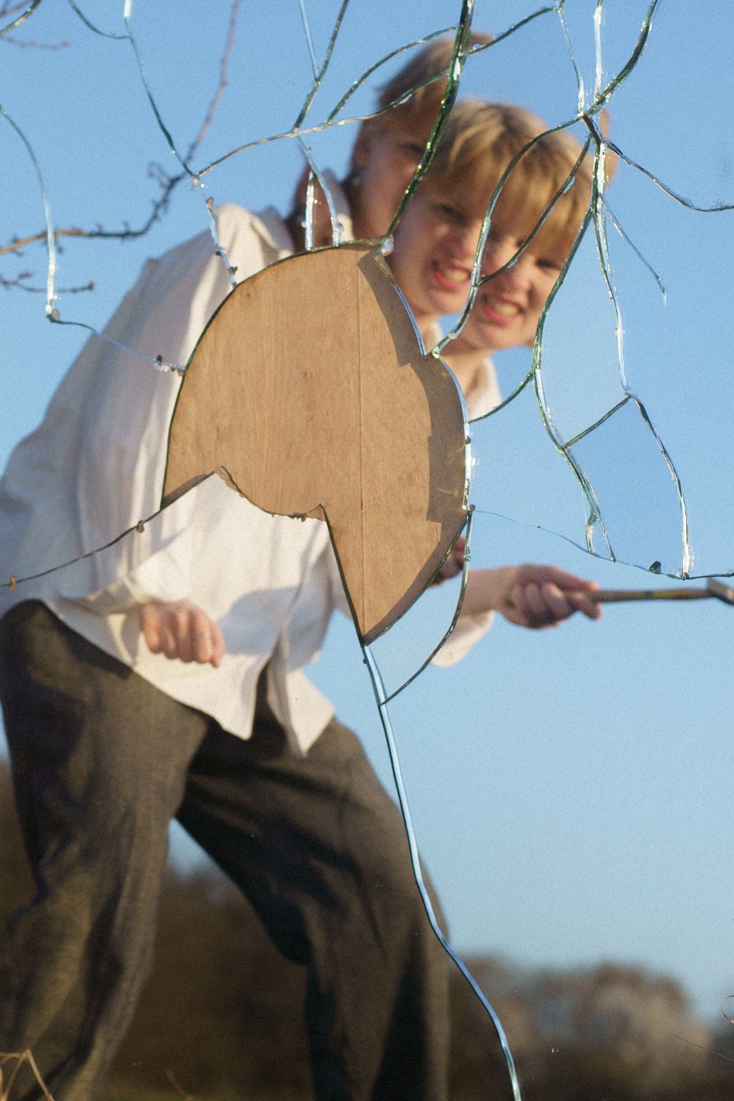 Someone holding a tambourine outdoors at dusk while wearing a white shirt and dark pants against a blue sky.