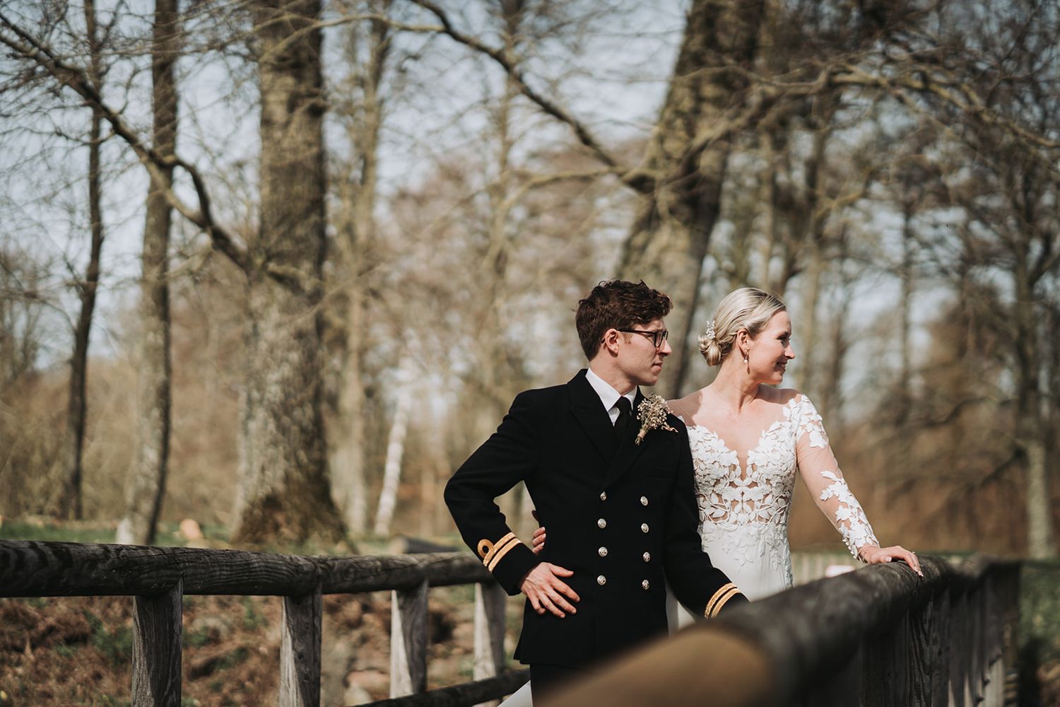 A romantic forest photoshoot featuring a couple against a backdrop of barren winter trees and natural light.