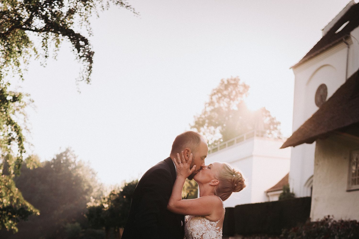 Warm sunlight illuminates an intimate moment against a white building exterior.
