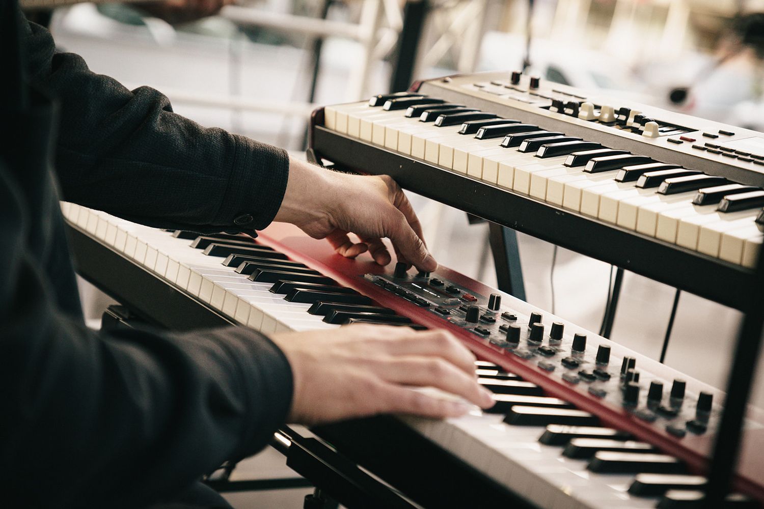 Close up view of hands playing piano keys in moody lighting with shallow depth of field.