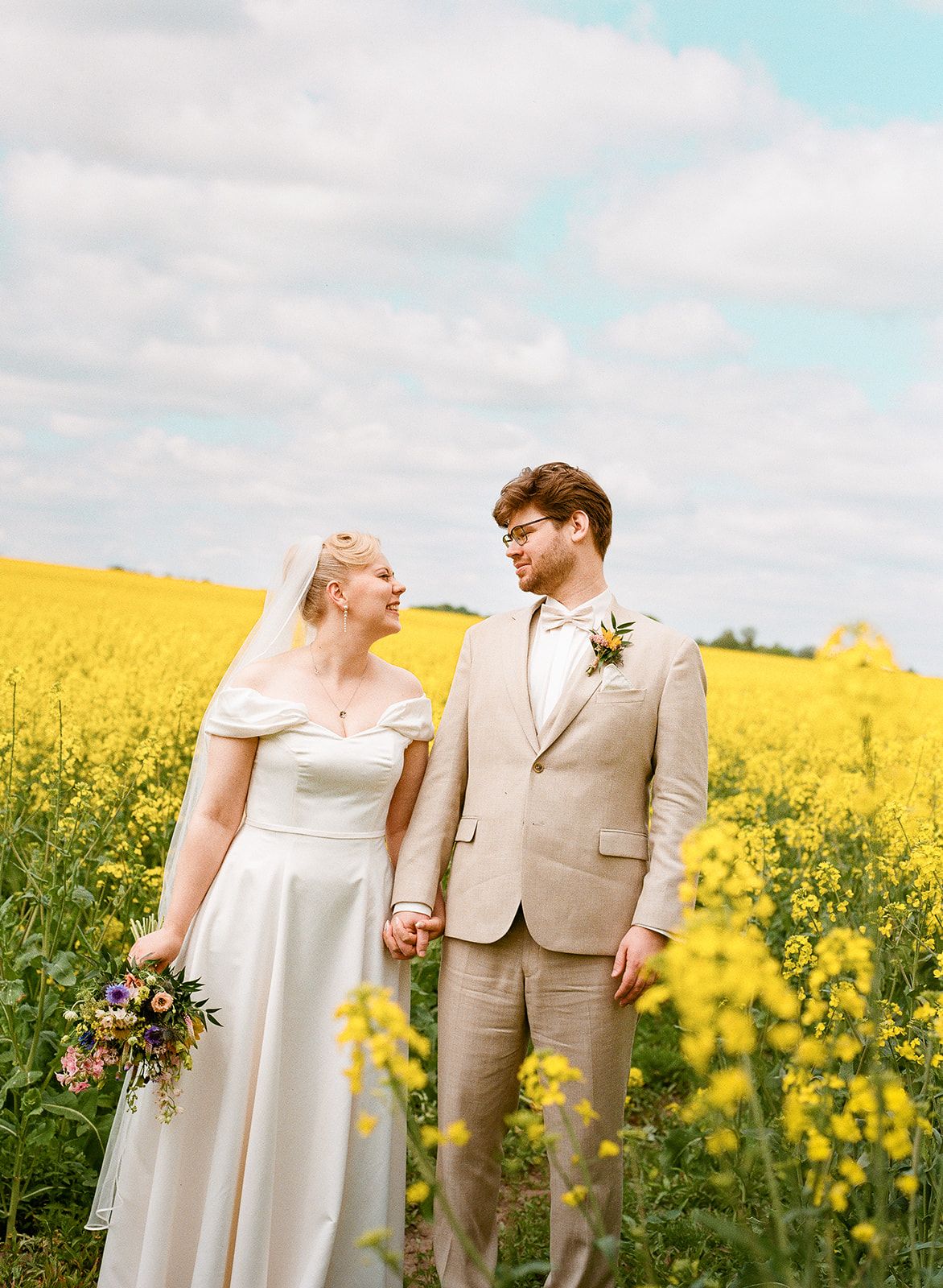 A romantic moment between newlyweds in a vibrant yellow canola field.