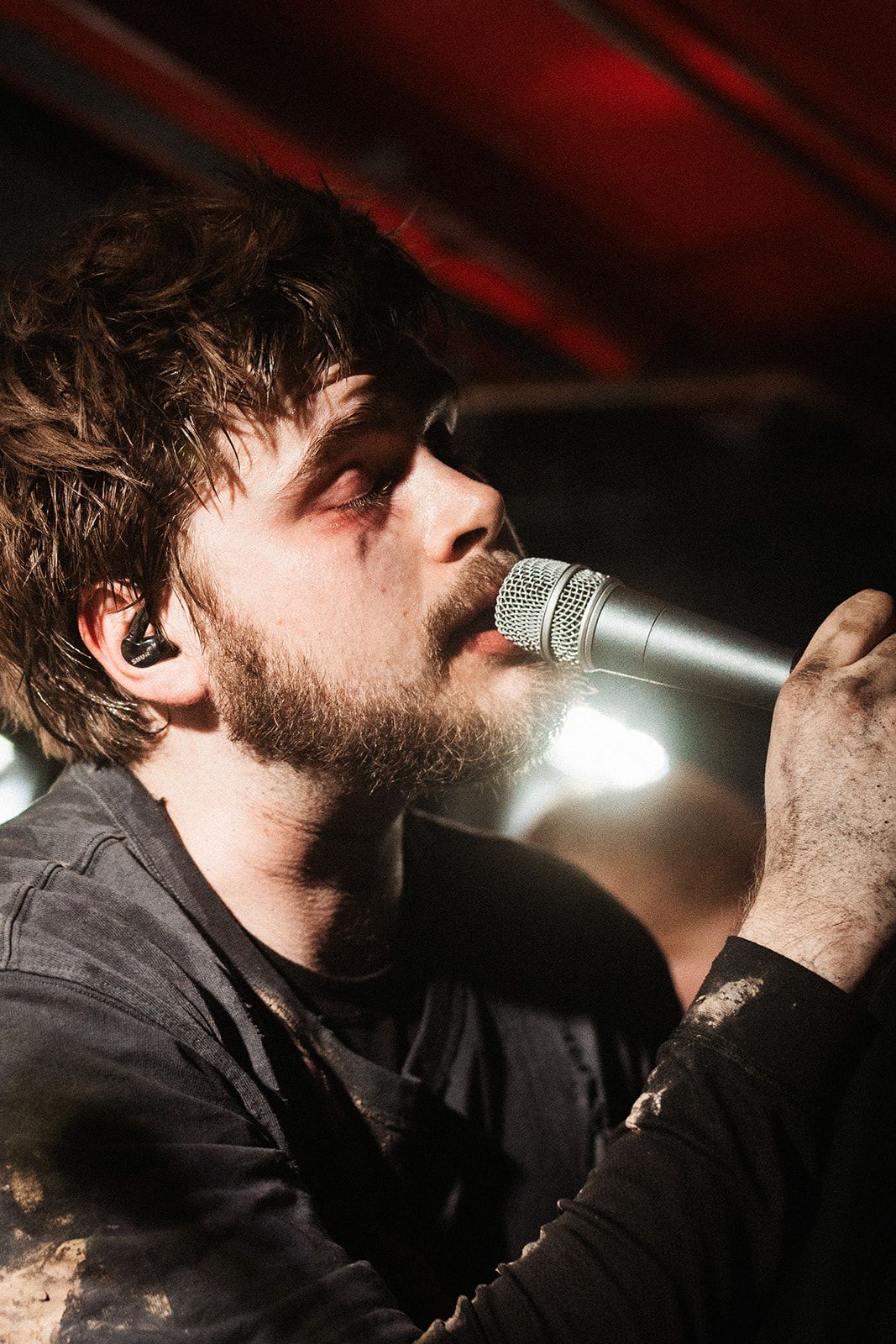 Close up shot of a vocalist singing into a microphone in dramatic lighting.