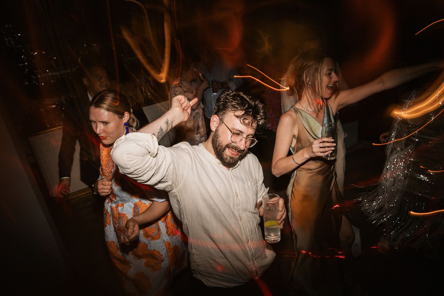 People dancing enthusiastically at a nightclub party with motion blur and warm lighting effects in the background.