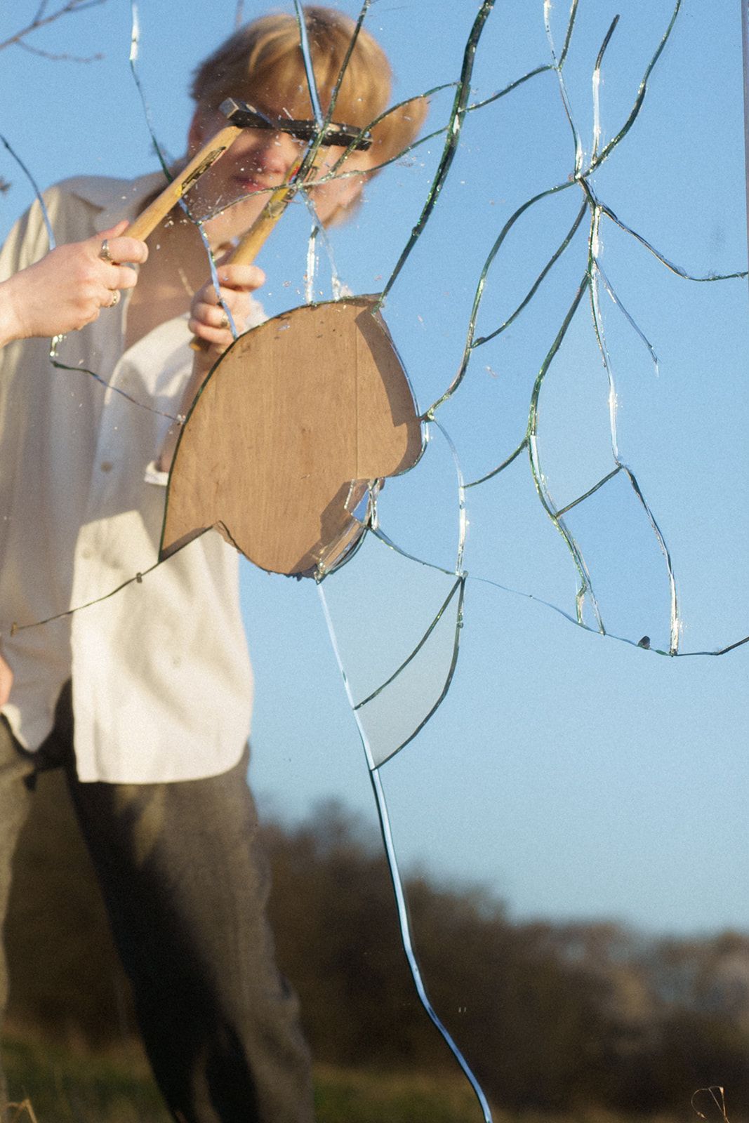 A person in light colored clothing plays a violin outdoors with string lights hanging in the background.