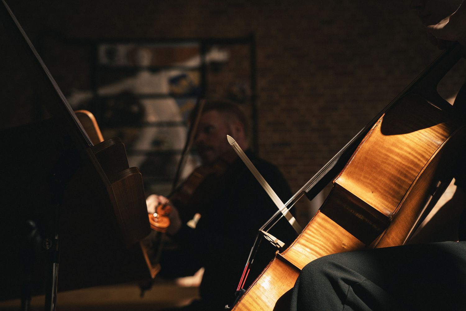 A closeup of a cello or violin being played in a dimly lit concert hall with dramatic lighting.