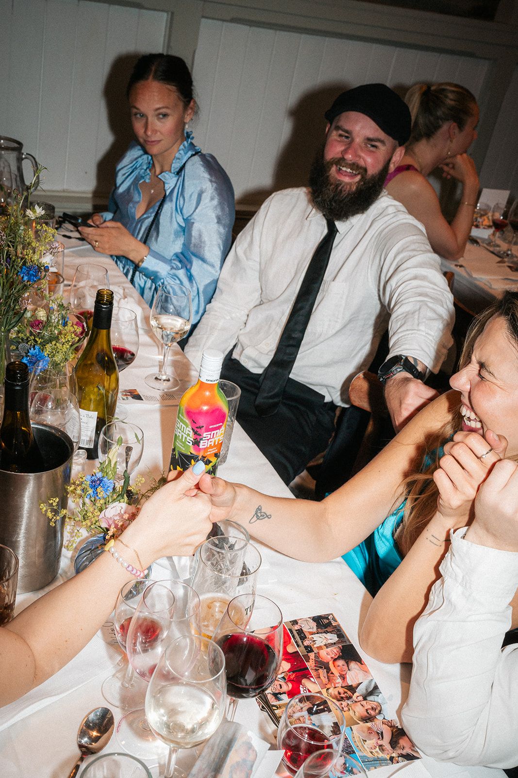 Dinner party scene with guests seated at a table with wine glasses and festive decorations.