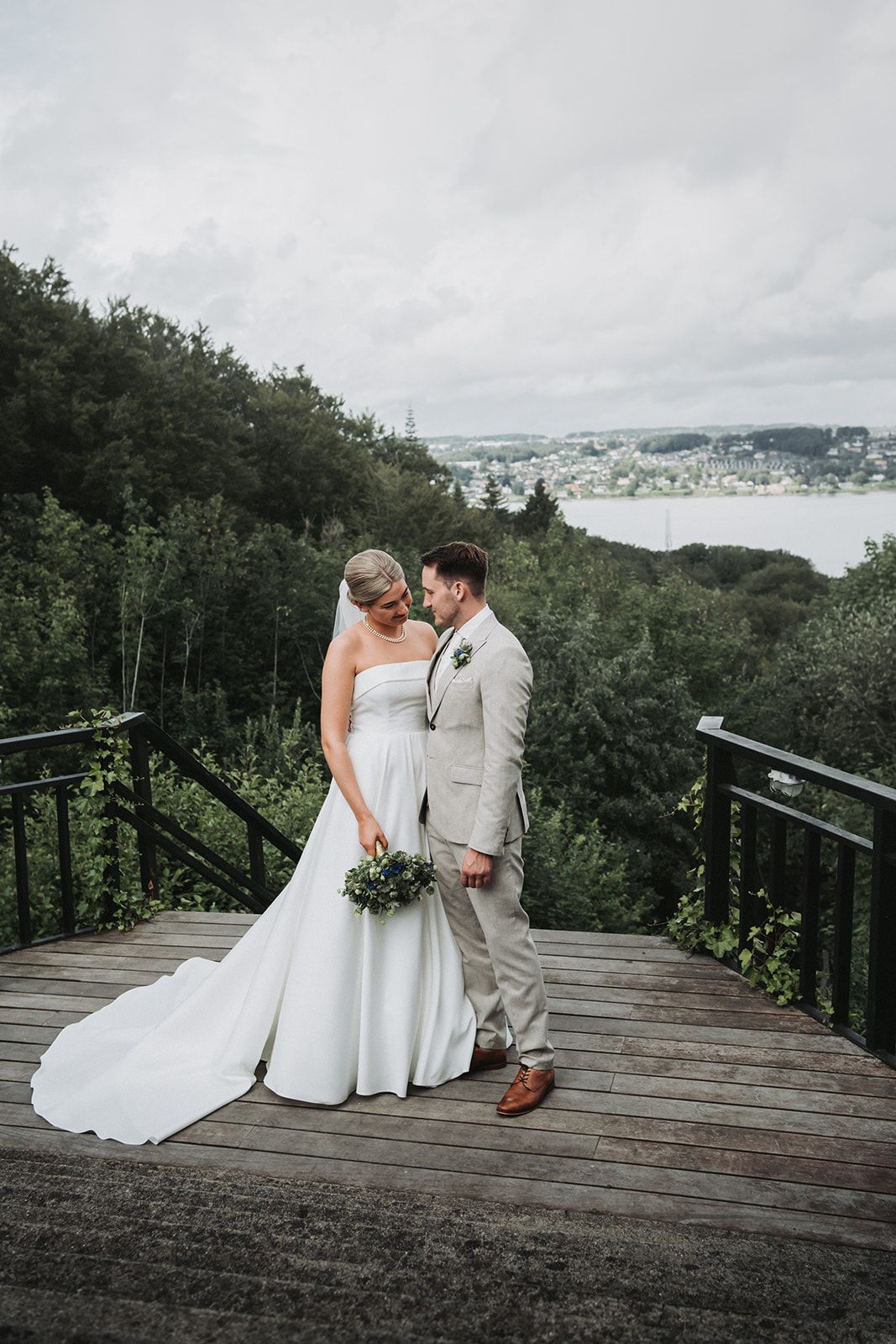 A set of romantic wedding photos taken on a wooden deck overlooking a scenic wooded hillside.