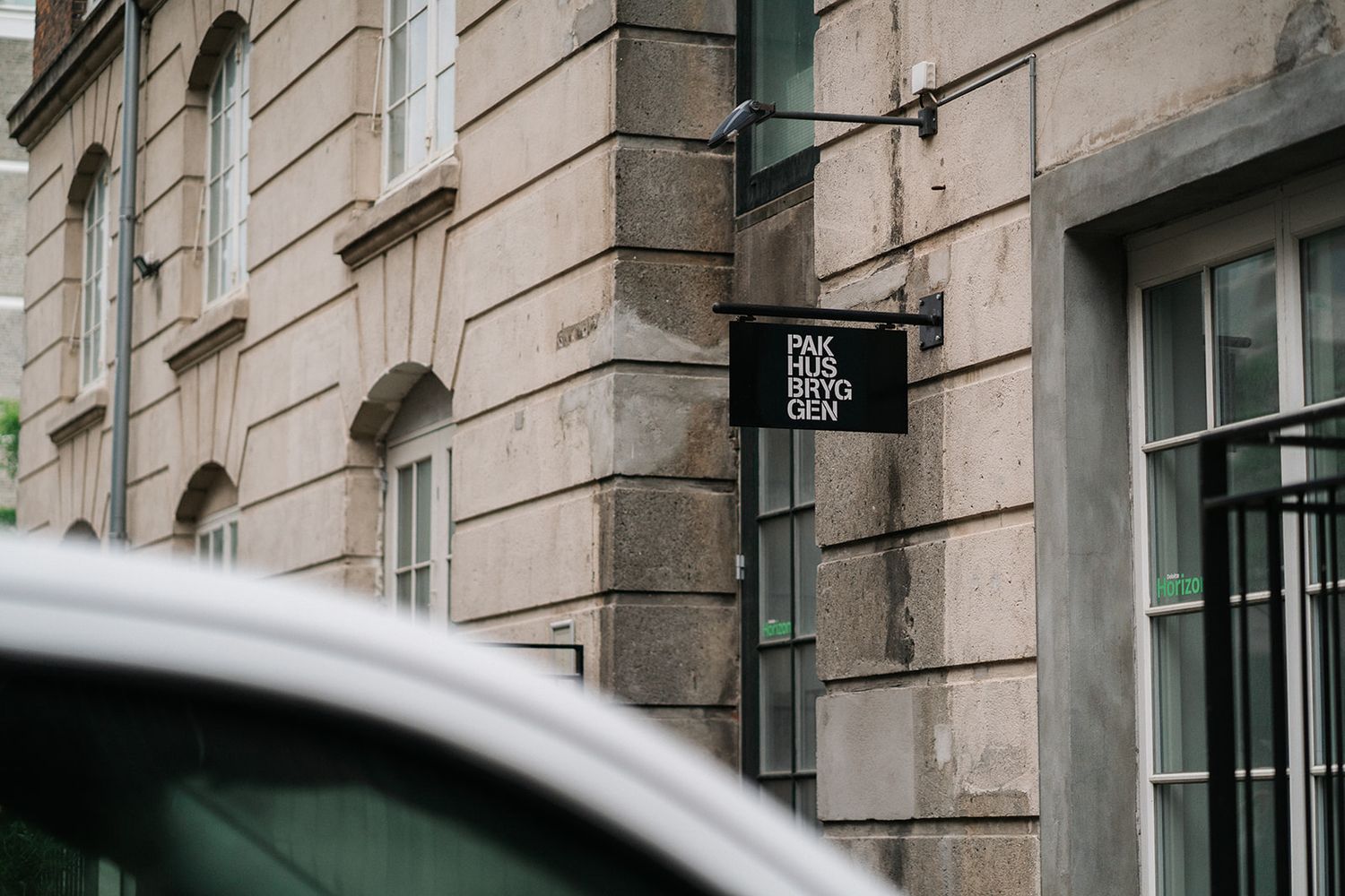 A modern gray compact electric car is parked on a cobblestone street near historic stone buildings.
