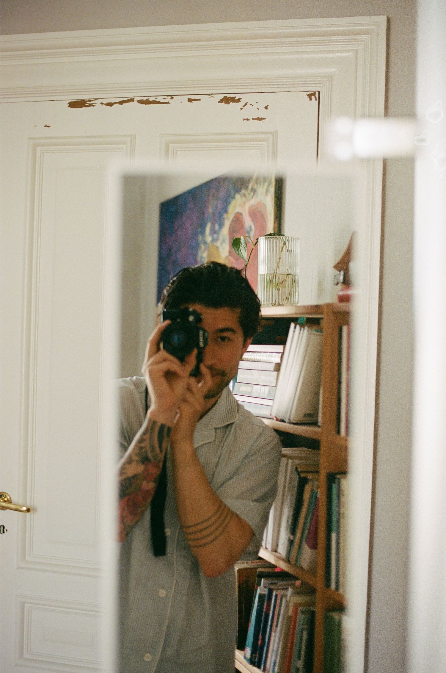 Three connected mirror reflections show a photographer in casual attire taking a picture in an interior space.