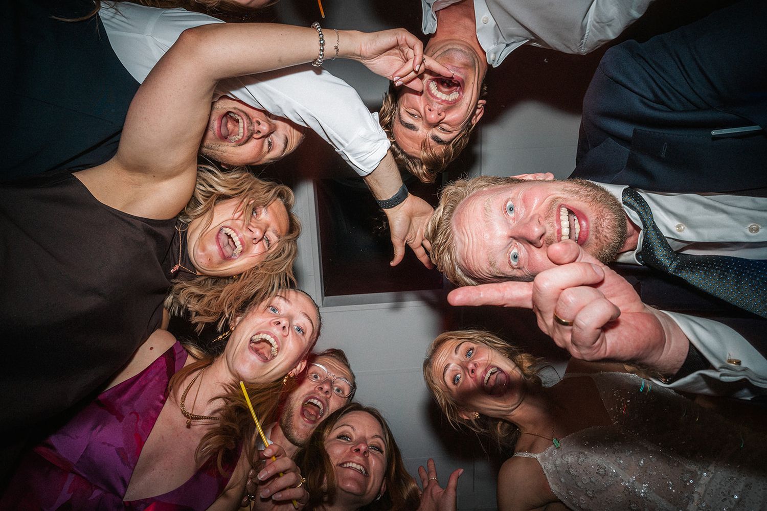 A fun group huddle photo taken from below shows people making silly faces while gathered in a circle.
