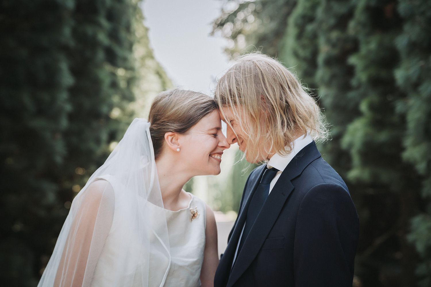 A romantic wedding couple shares tender moments among evergreen trees in a sequence of intimate portraits.