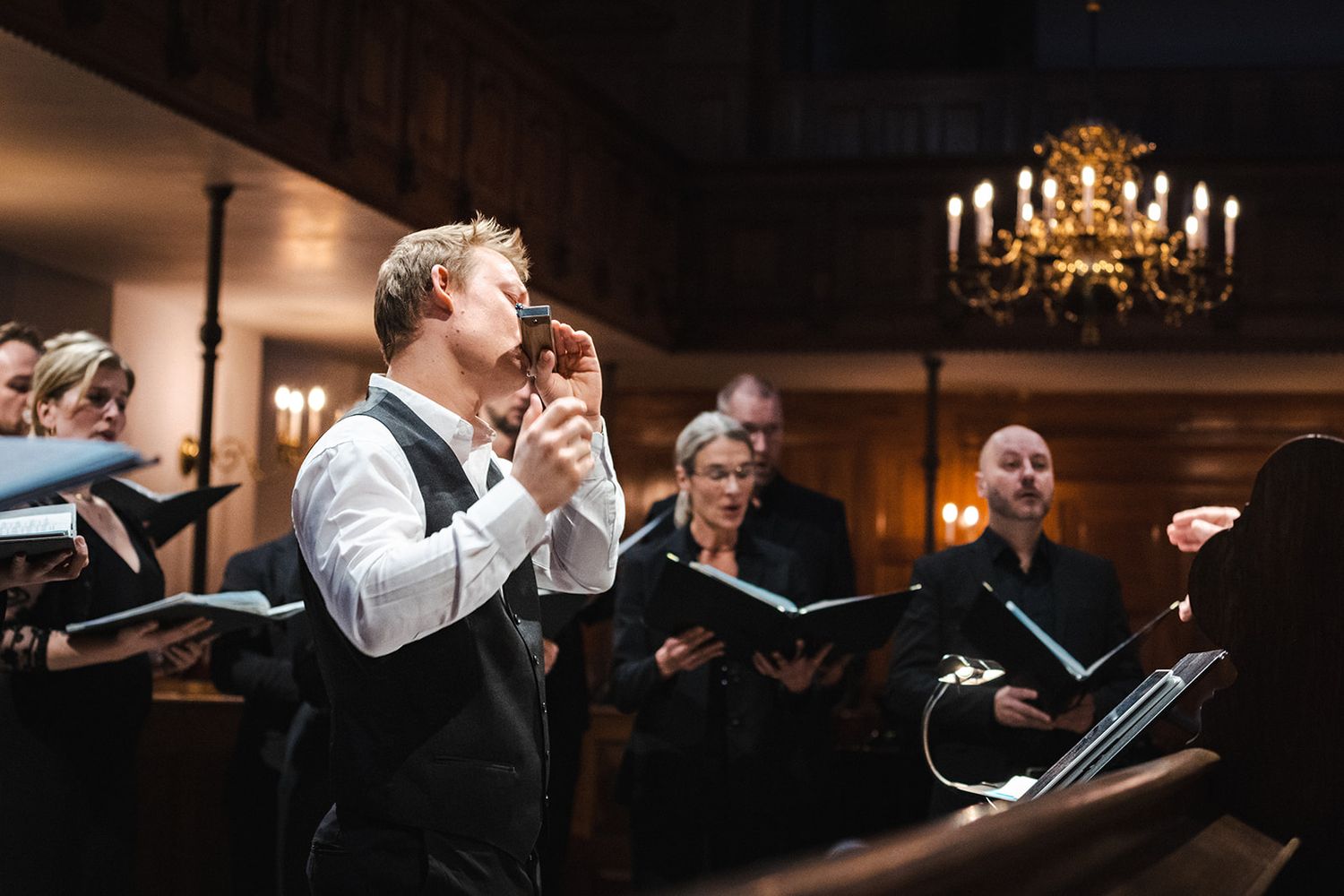 Guests dancing and celebrating at an elegant wedding reception under warm chandelier lighting in a rustic venue.