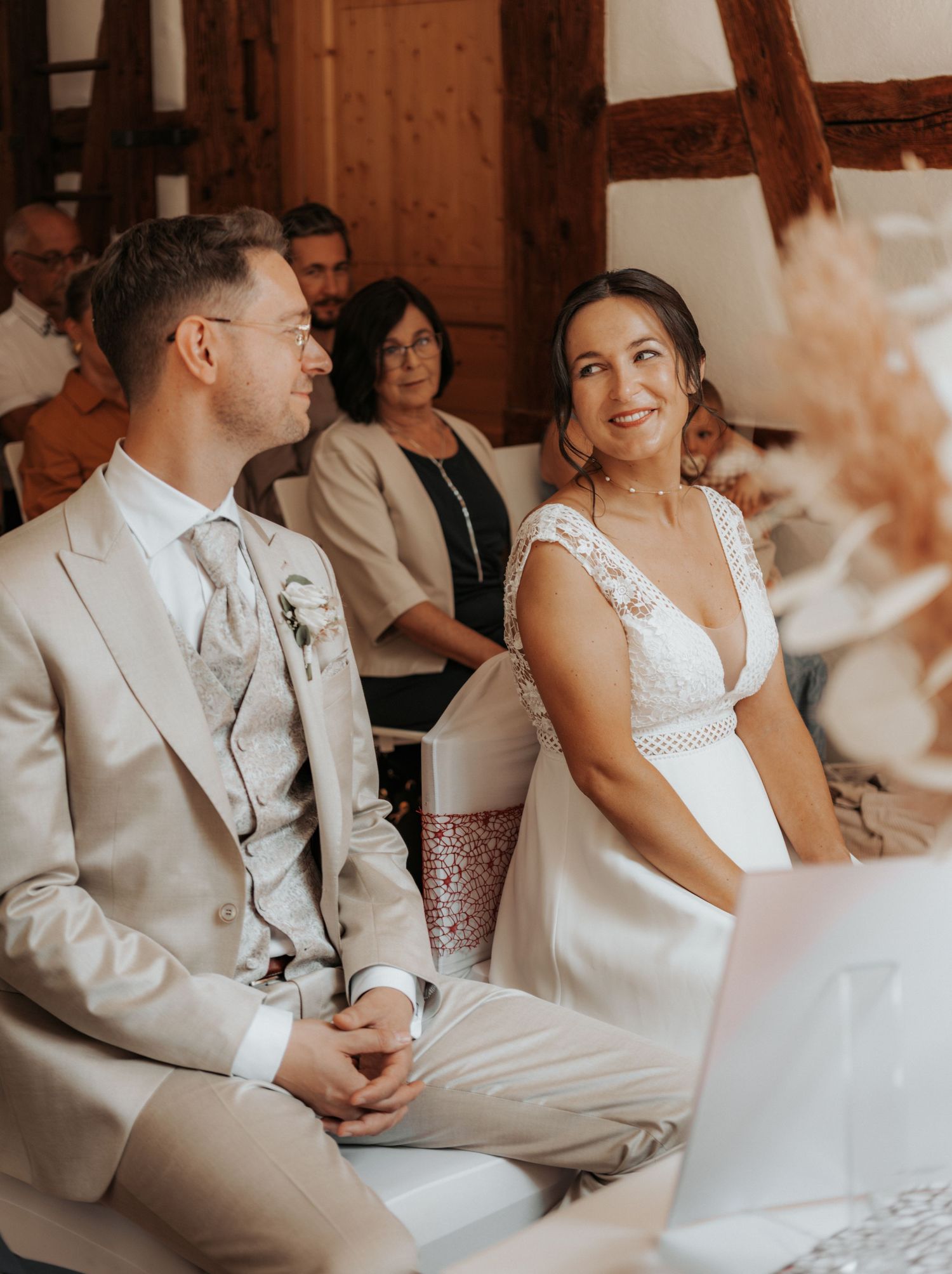 A couple in wedding attire share an intimate moment during their ceremony in a warm-toned indoor setting.
