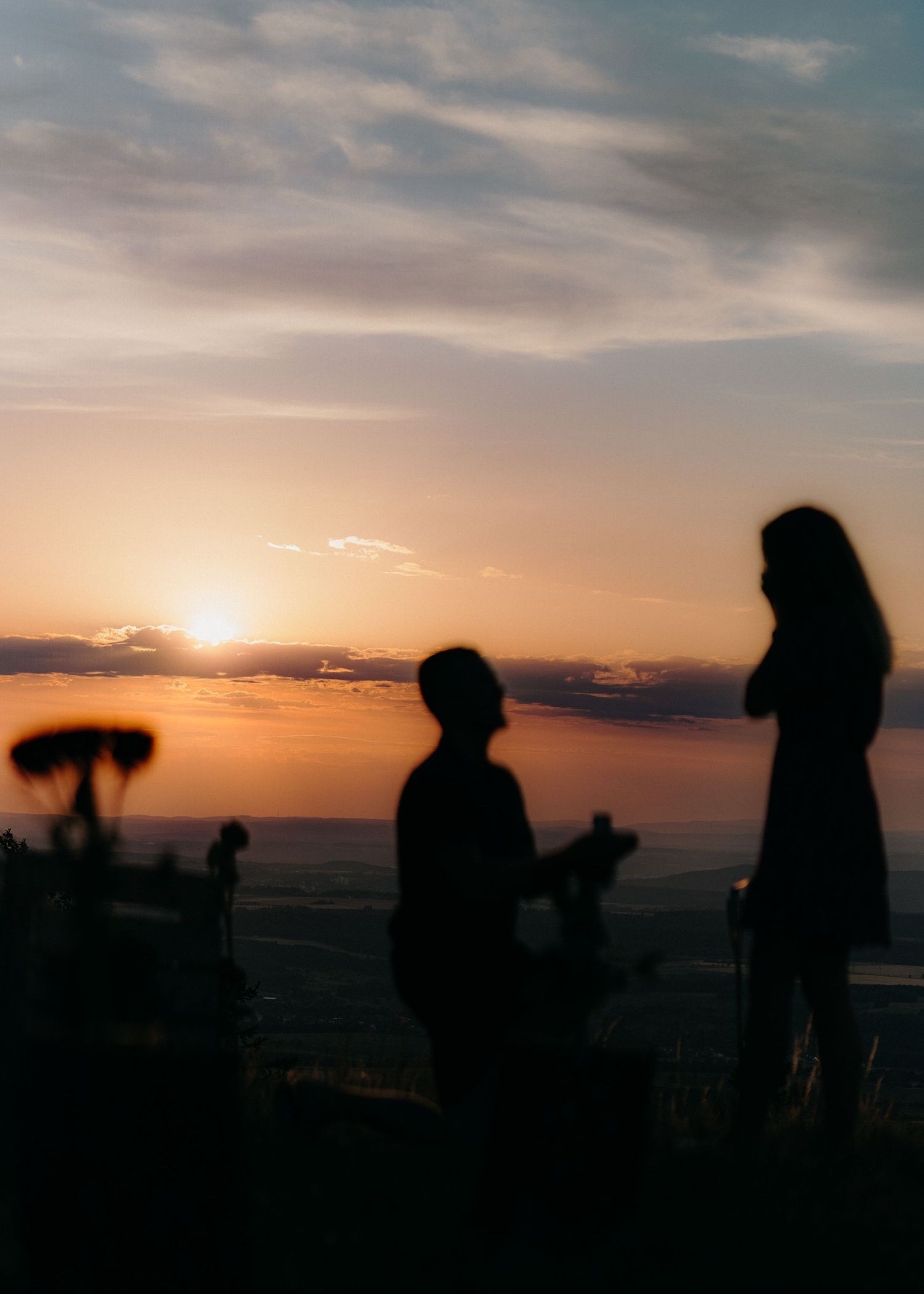 Silhouettes of people watching a dramatic orange sunset over the ocean horizon create a panoramic sequence.