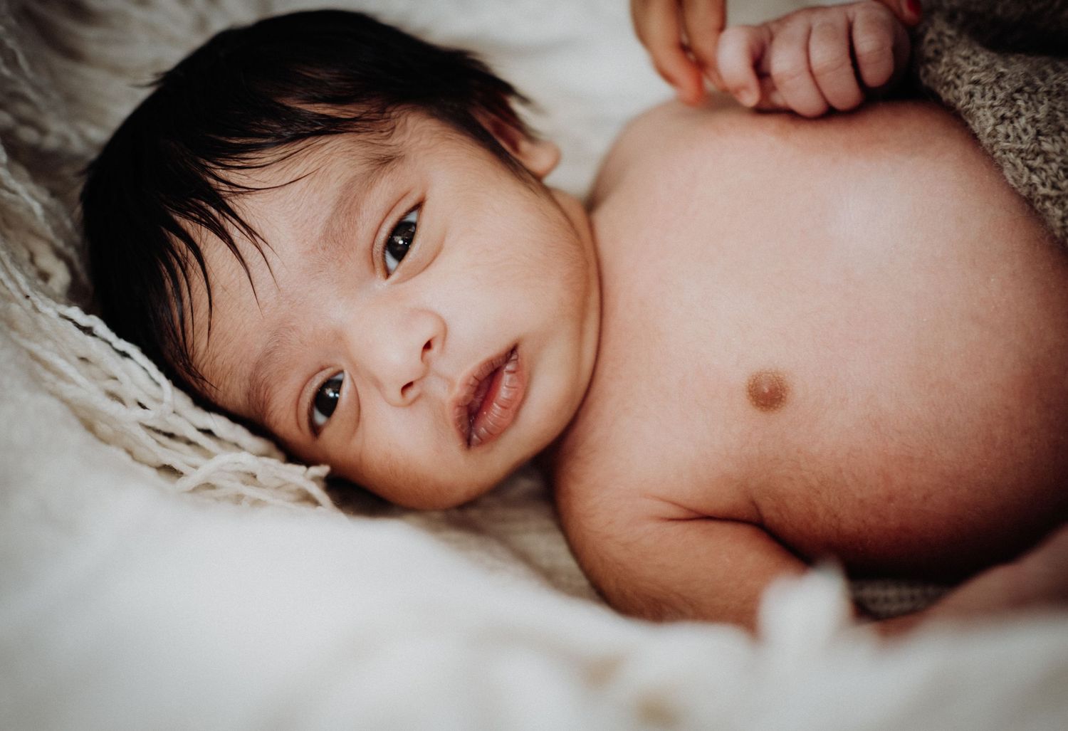 A series of black and white photographs showing a baby lying down in a soft blanket.