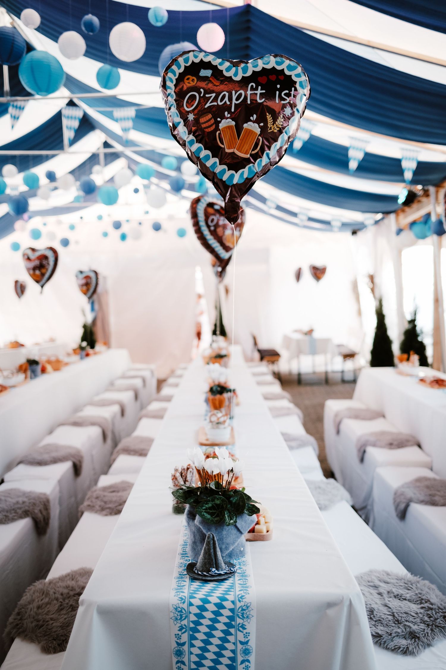 Elegant wedding reception setup with white tables, gray chairs, and heart-shaped balloon decorations in a modern venue.