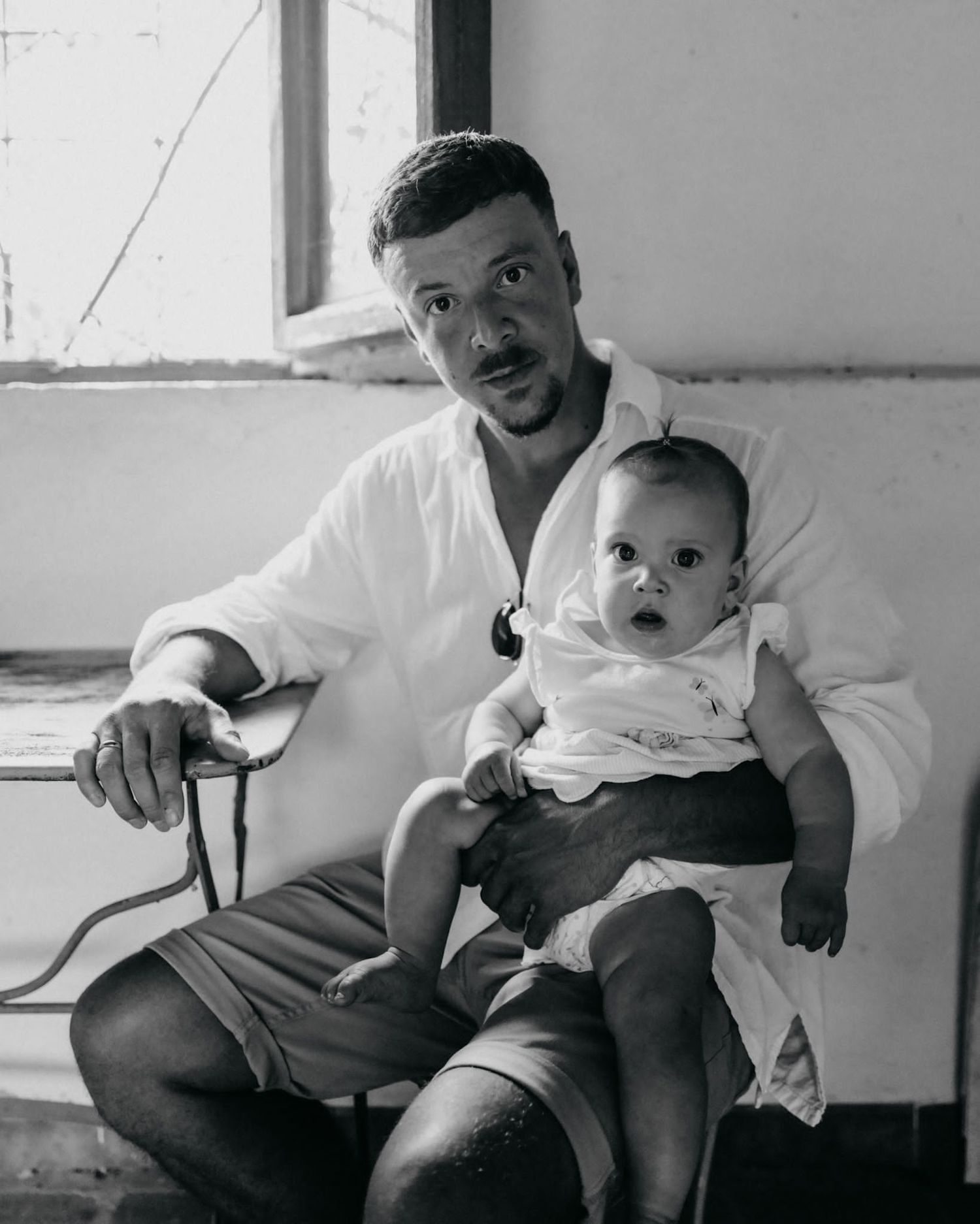 A series of black and white photos showing a baby sitting on a couch in different expressive poses.