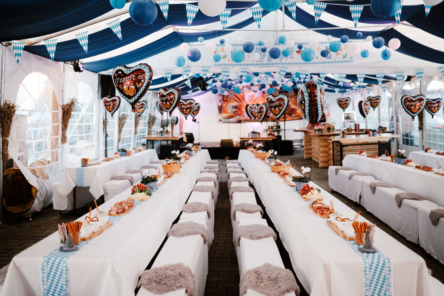 A wedding reception venue decorated in blue and white with elegant table settings and flowing fabric drapes.