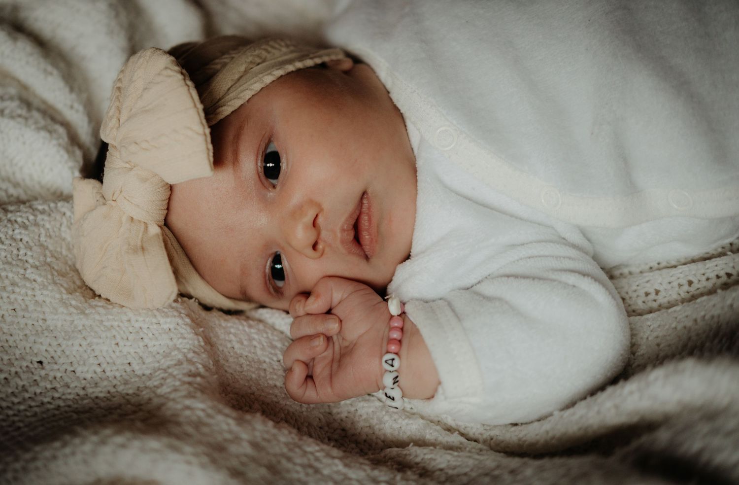 A series of black and white photos showing a baby lying on white bedding in various poses.