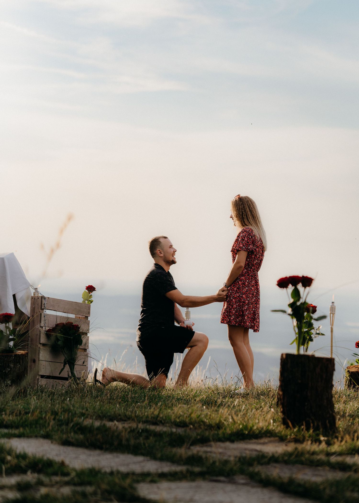 A romantic marriage proposal sequence captured at sunset with a couple on a hilltop path.